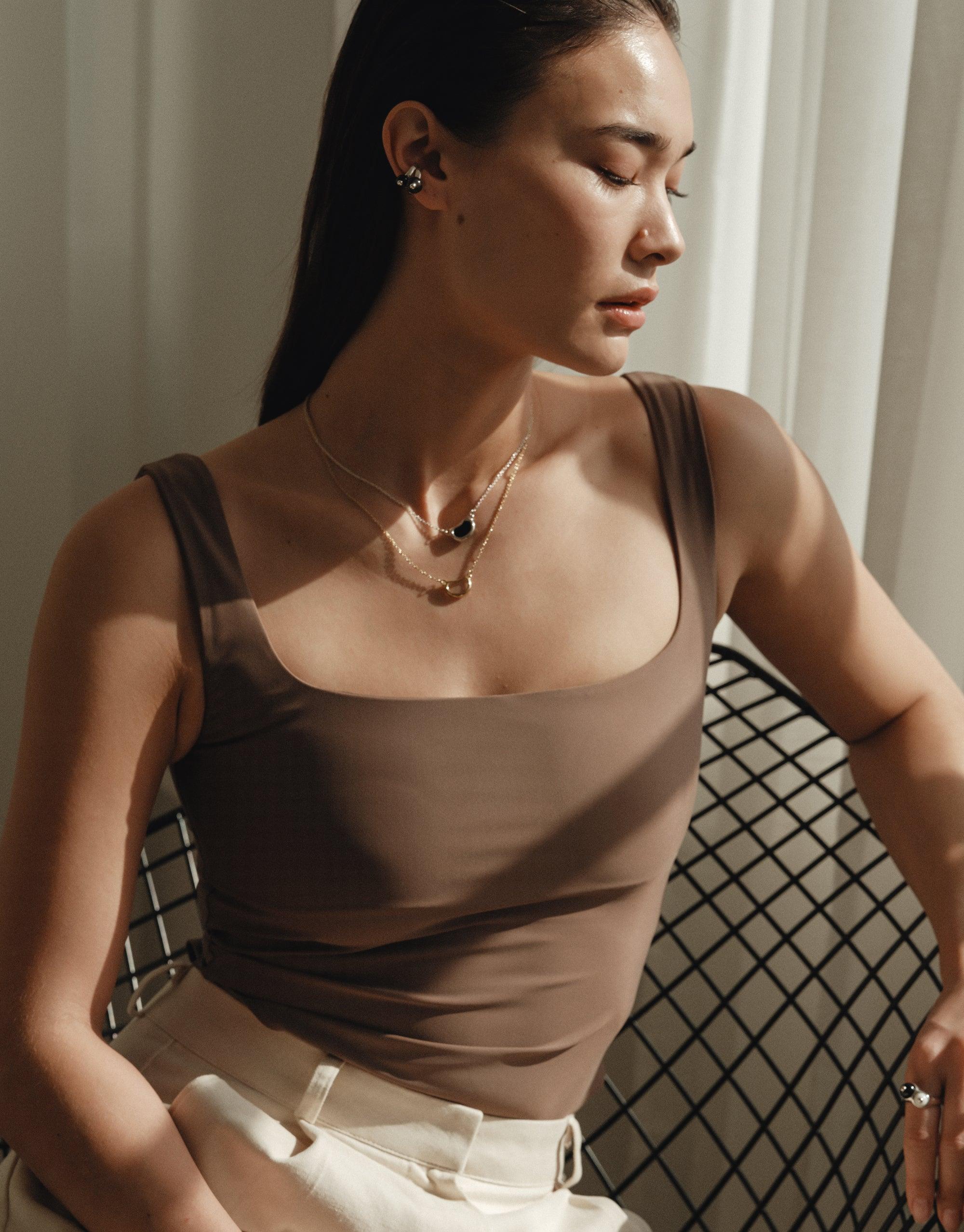 Elegant model wearing Bean Necklace, featuring organic shapes inspired by nature's creativity. Delicate curves and intricate patterns showcase the beauty of legume-inspired design. Soft lighting emphasizes the necklace's unique form. Bean Necklace by CLED.