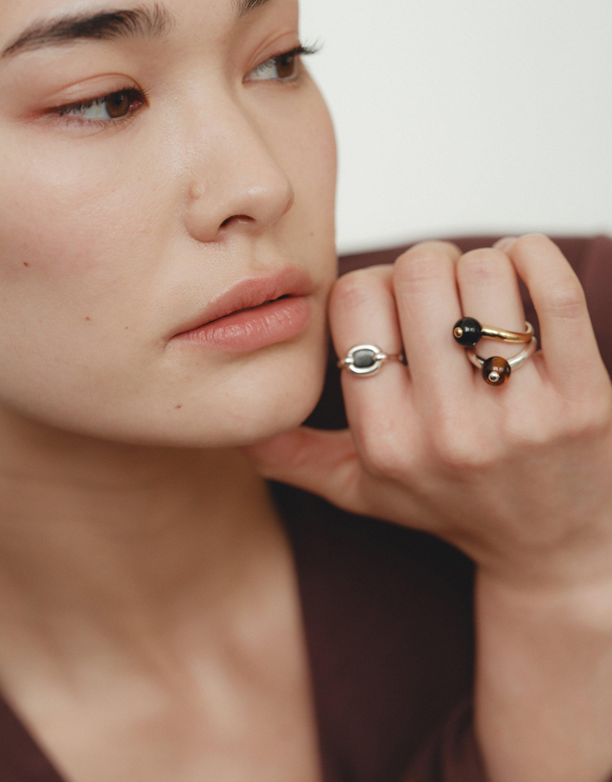 Close-up of a model's hand showcasing unique nature-inspired rings, including the Pea Curve Ring | Large. The jewelry features organic shapes and soft curves, reflecting the beauty of legumes and natural growth. Elegant and transformative design by CLED.