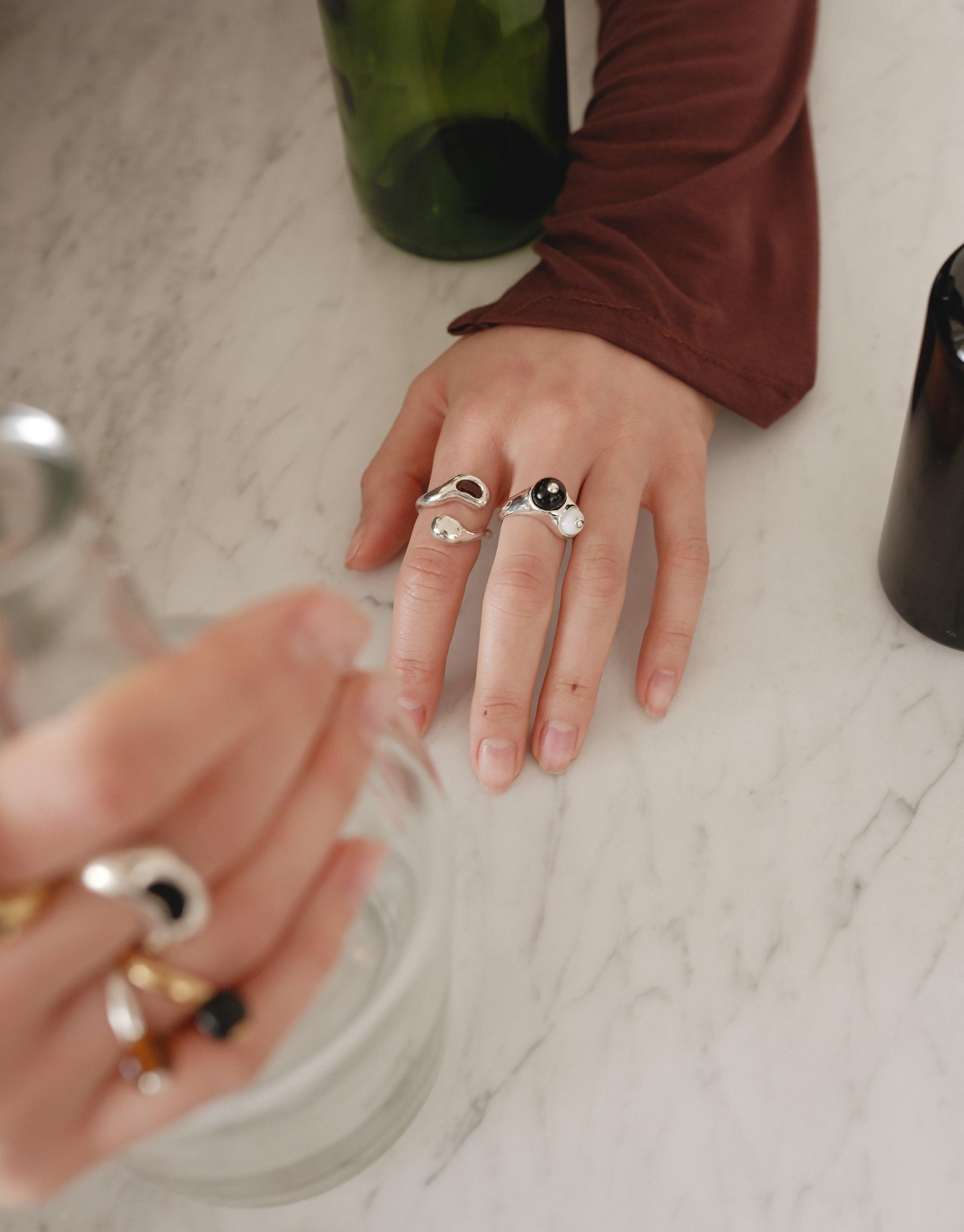 Sprout Ring showcased on a hand adorned with multiple rings, reflecting CLED's eco-conscious ethos, inspired by legume plant curves, handmade from repurposed glass for sustainable elegance.