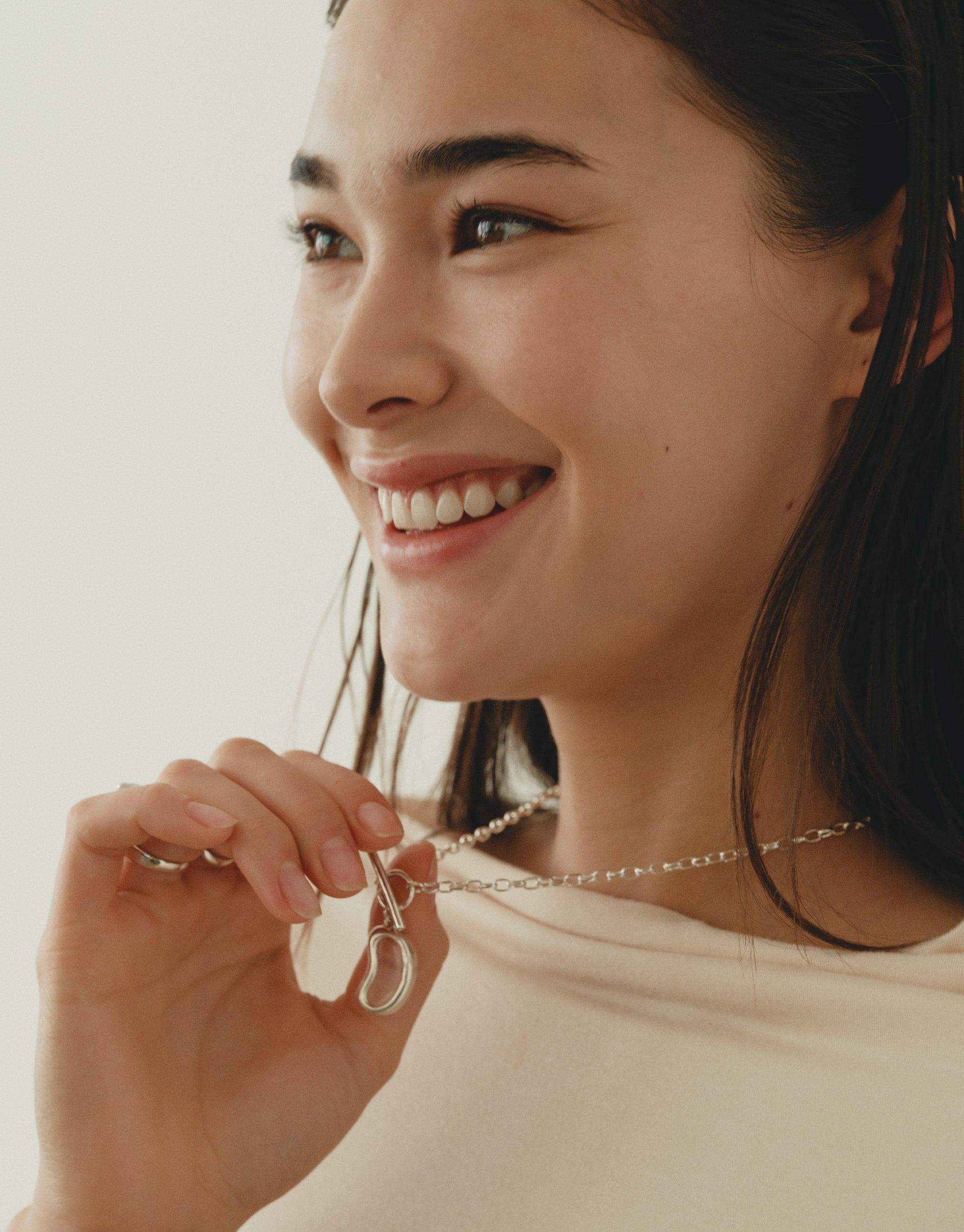 Close-up of a person wearing the Bean Toggle Necklace, showcasing its organic shape inspired by nature's creativity. The necklace features a unique legume-inspired design, capturing the essence of growth and transformation. Bean Toggle Necklace by CLED.