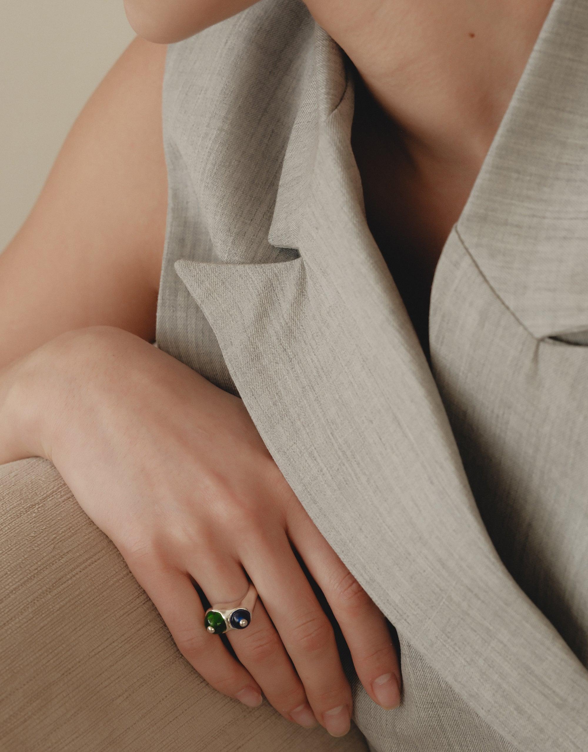 Elegant hand wearing Pod Ring, inspired by organic legume shapes. Nature-inspired jewelry showcasing soft curves and intricate patterns. Stylish accessory complementing neutral-toned outfit, embodying growth and transformation. CLED Pod Ring.