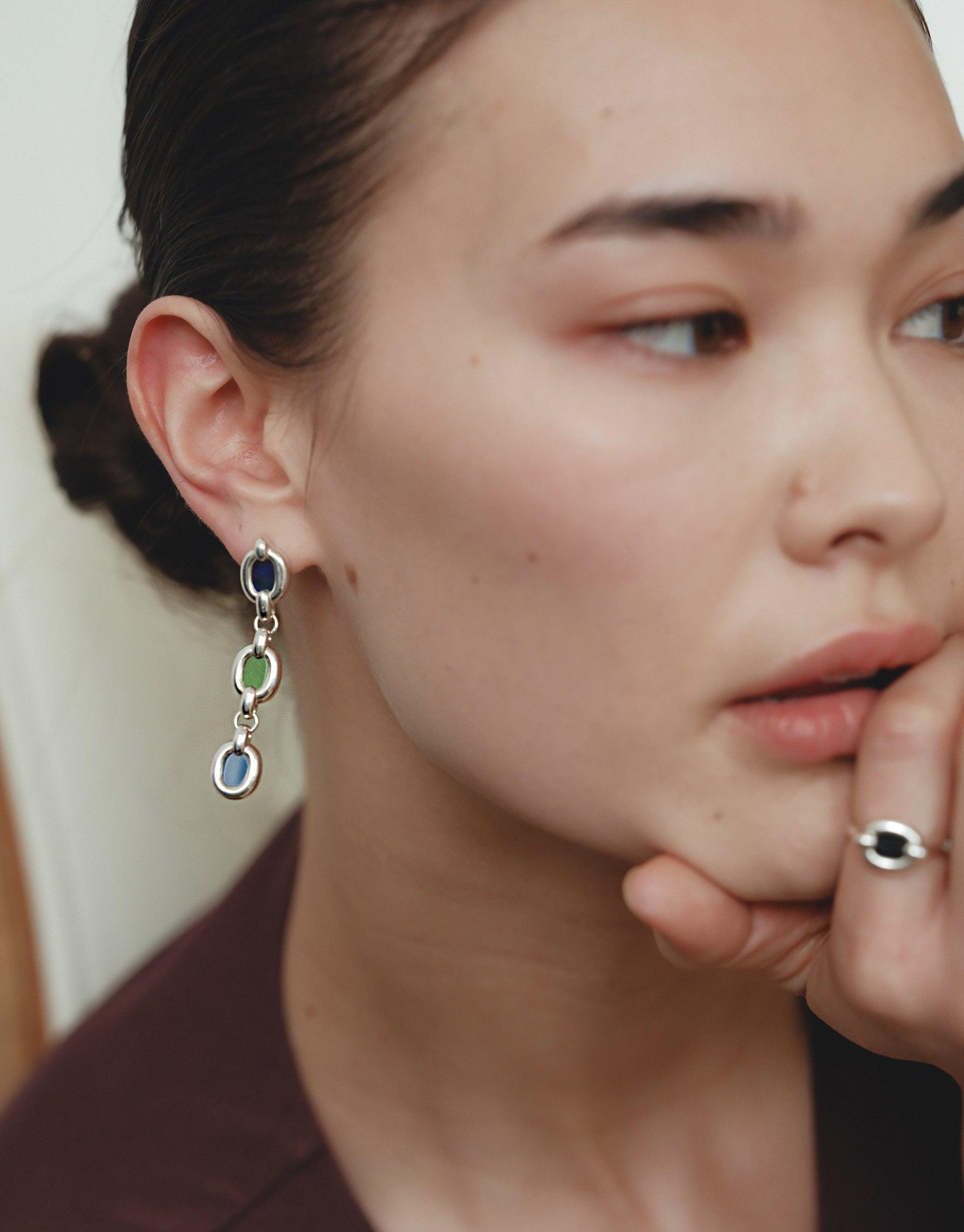 Trio Core Loop Earrings showcased by a woman with hand on chin, highlighting eco-conscious design with silver loops from repurposed glass, symbolizing unity and sustainability in CLED's collection.