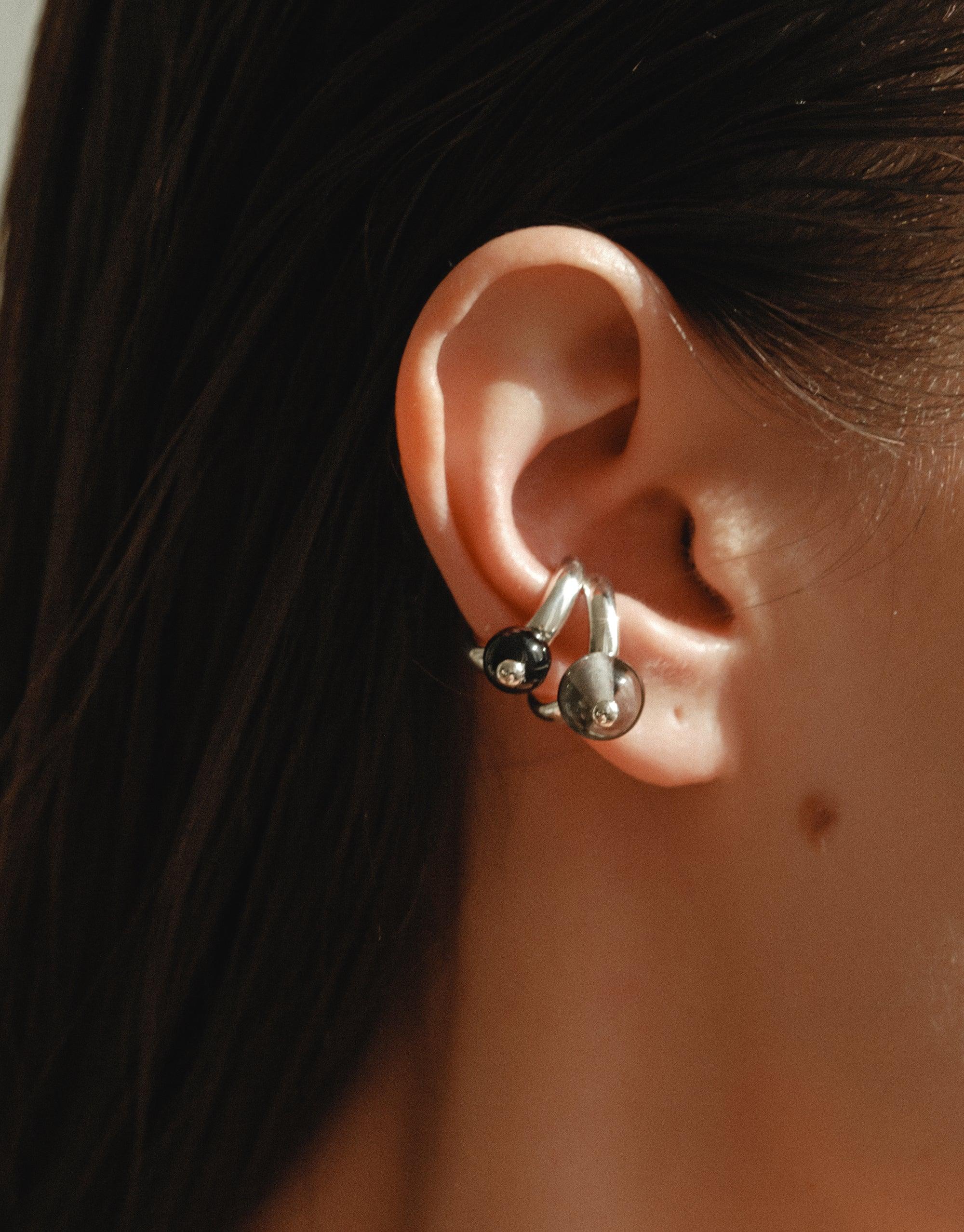 Close-up of an ear wearing a silver Pea Ear Cuff | Large, showcasing its organic shape inspired by nature's creativity. The cuff elegantly wraps around the ear, capturing the essence of growth and transformation in its design. CLED