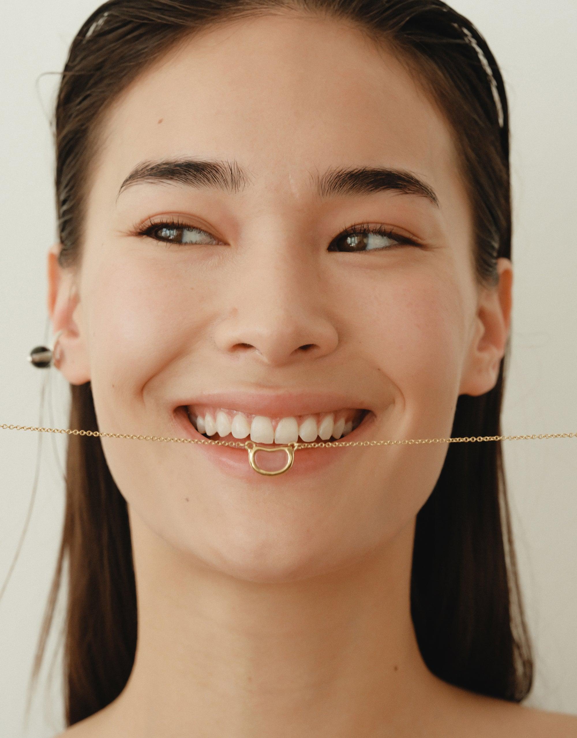 Close-up of a smiling model wearing the Pea Ear Cuff | Small, showcasing its delicate design inspired by nature's organic shapes. The cuff elegantly complements the wearer's ear, reflecting the collection's theme of growth and transformation. A unique piece that captures the essence of natural beauty and creativity by CLED.