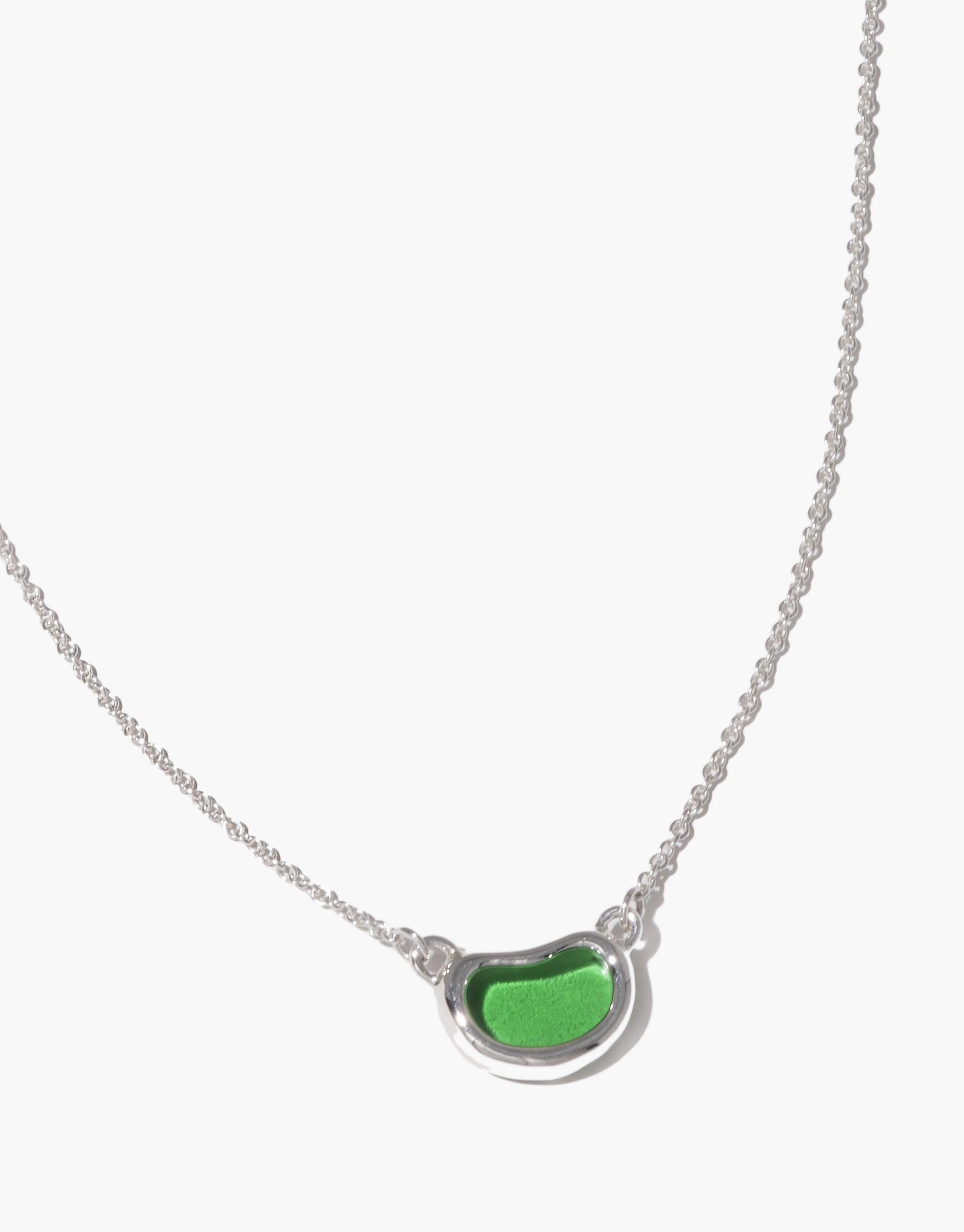 Elegant silver necklace featuring a unique bean-shaped pendant with vibrant green enamel, inspired by nature's organic forms. The Bean Necklace showcases a delicate chain and minimalist design, perfect for everyday wear or special occasions. CLED