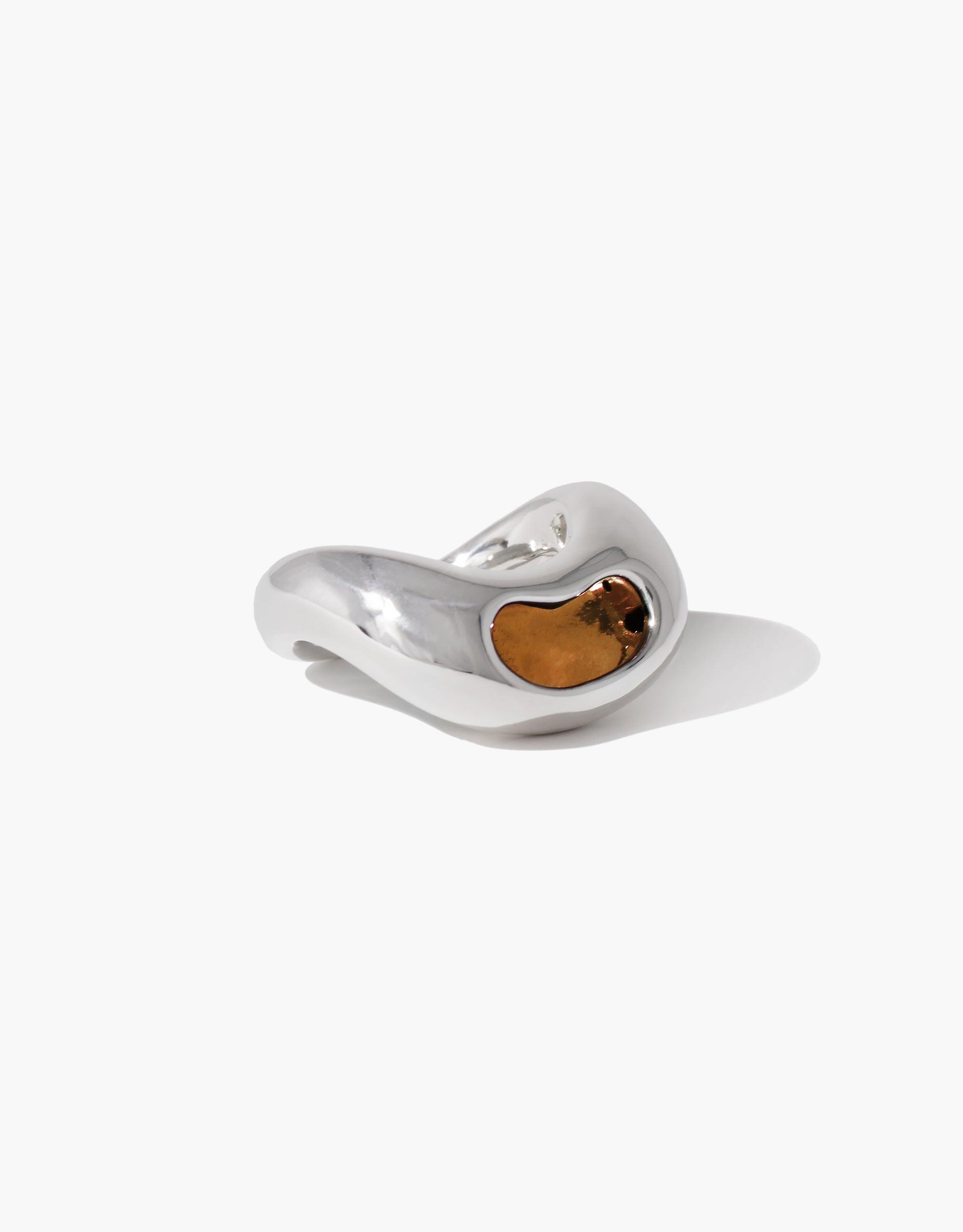 Elegant silver Bean Ring with amber-colored inlay, inspired by organic legume shapes. Smooth, curved design capturing nature's creativity. Unique jewelry piece embodying growth and transformation. CLED Bean Ring.