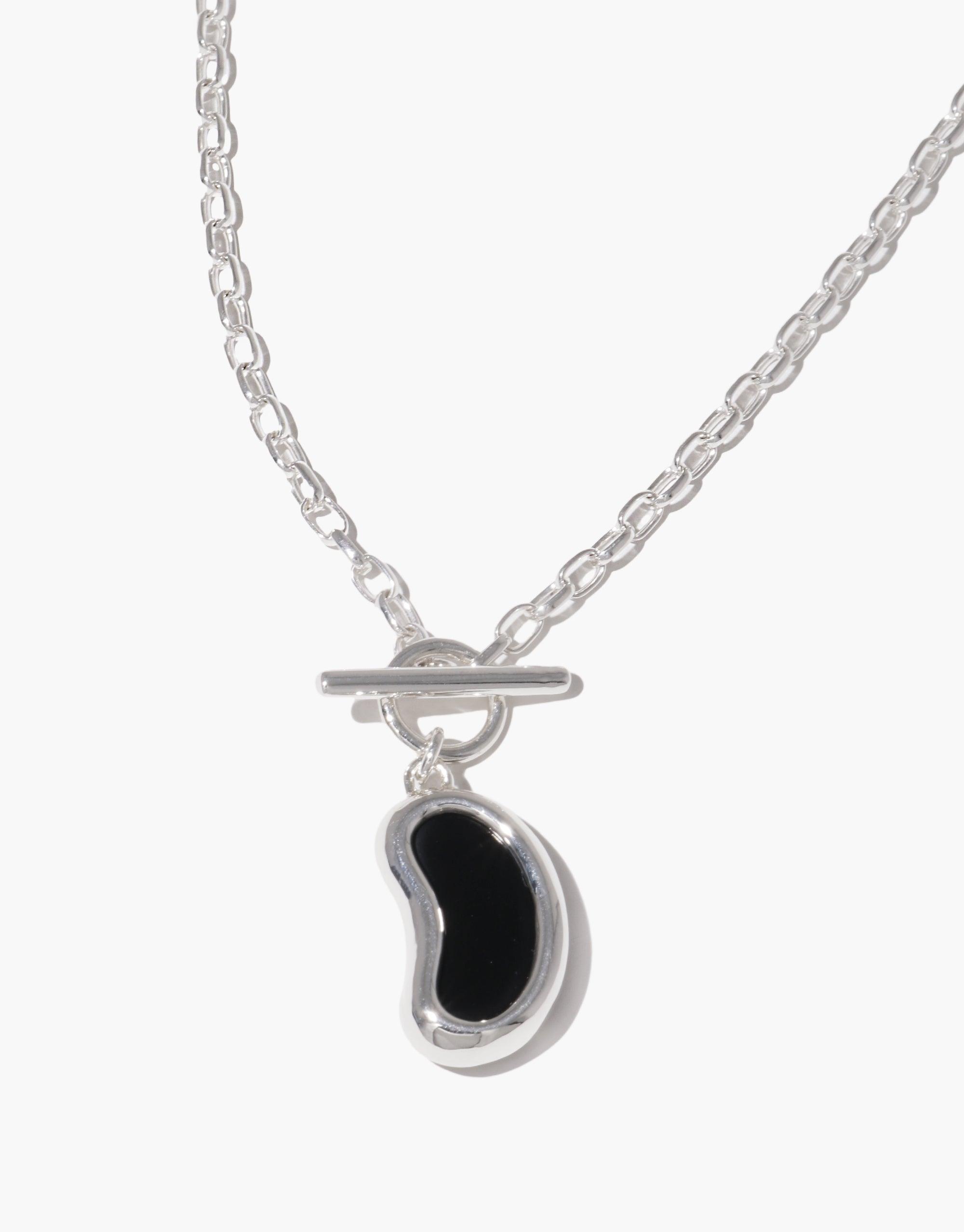 Elegant silver necklace featuring a unique bean-shaped toggle pendant in black, inspired by nature's organic forms. The Bean Toggle Necklace showcases a delicate chain and a stylish toggle clasp, embodying growth and transformation. Perfect for eco-conscious fashion enthusiasts. CLED