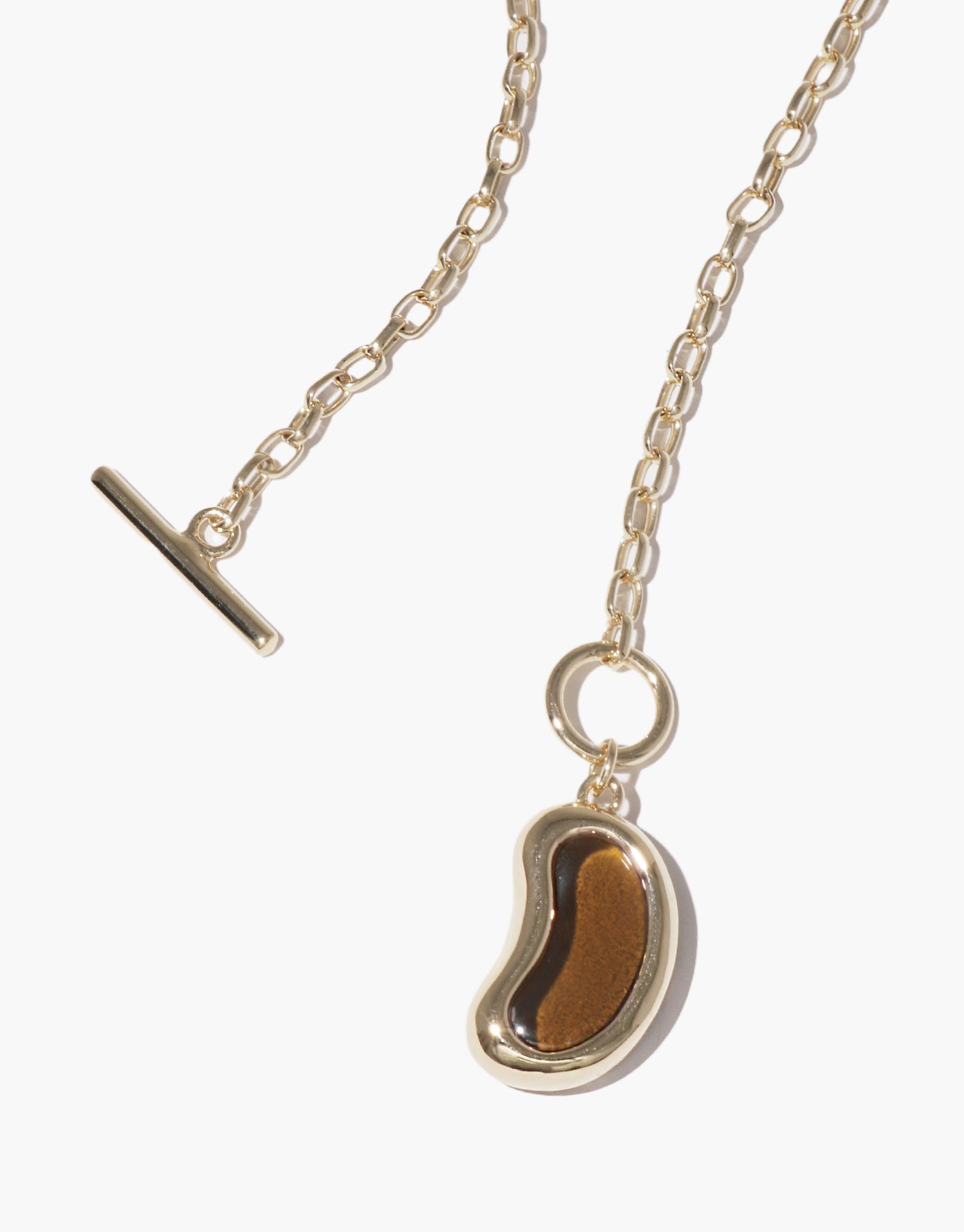Elegant gold chain necklace featuring a unique bean-shaped pendant, inspired by nature's organic forms. The Bean Toggle Necklace showcases a polished metallic finish, embodying growth and transformation. A sophisticated accessory that captures the essence of natural beauty. CLED