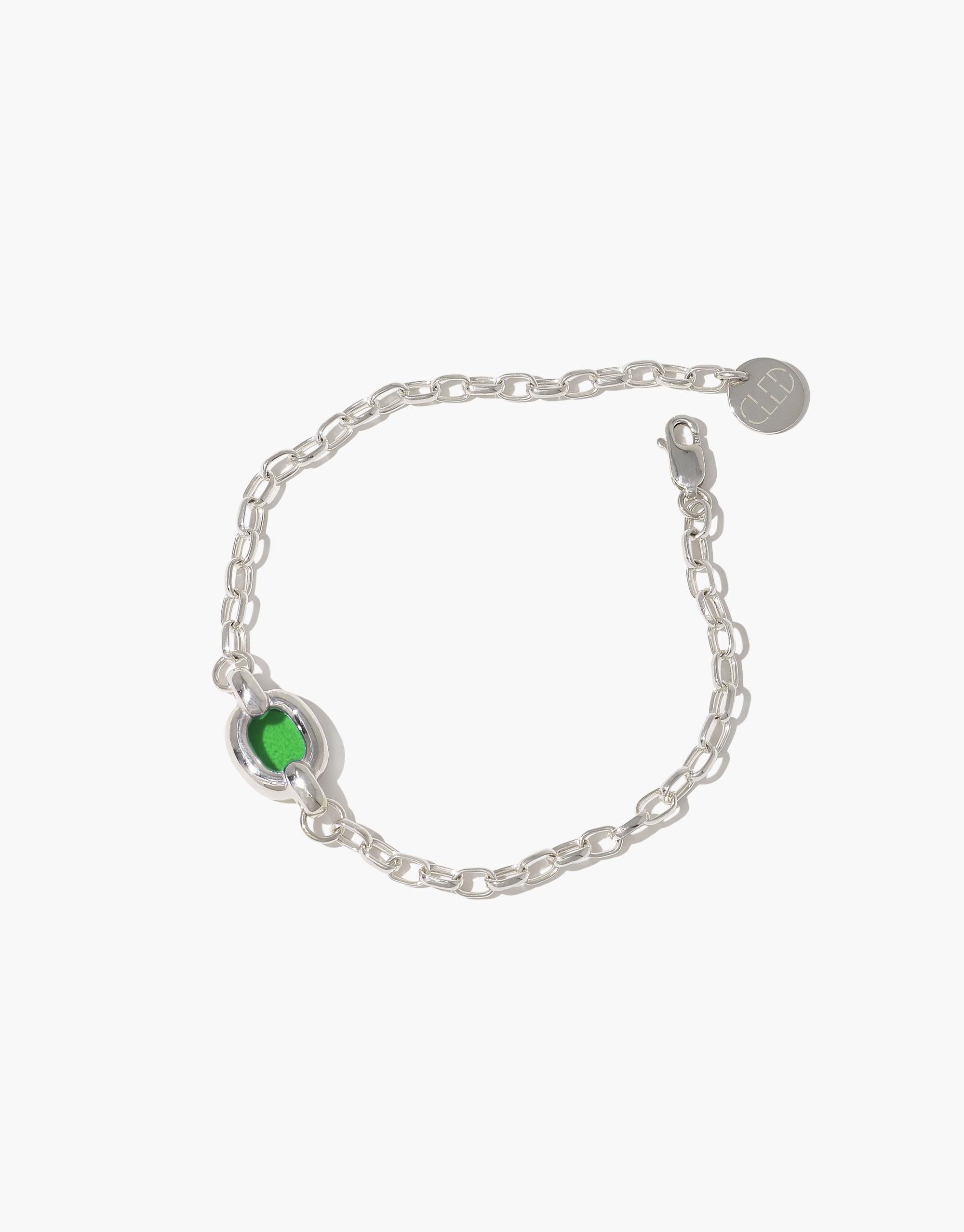 Elegant silver chain bracelet with green glass bead centerpiece, symbolizing unity and sustainability. Core Loop Bracelet features delicate links and a circular brand charm, representing connection and eco-conscious design by CLED.