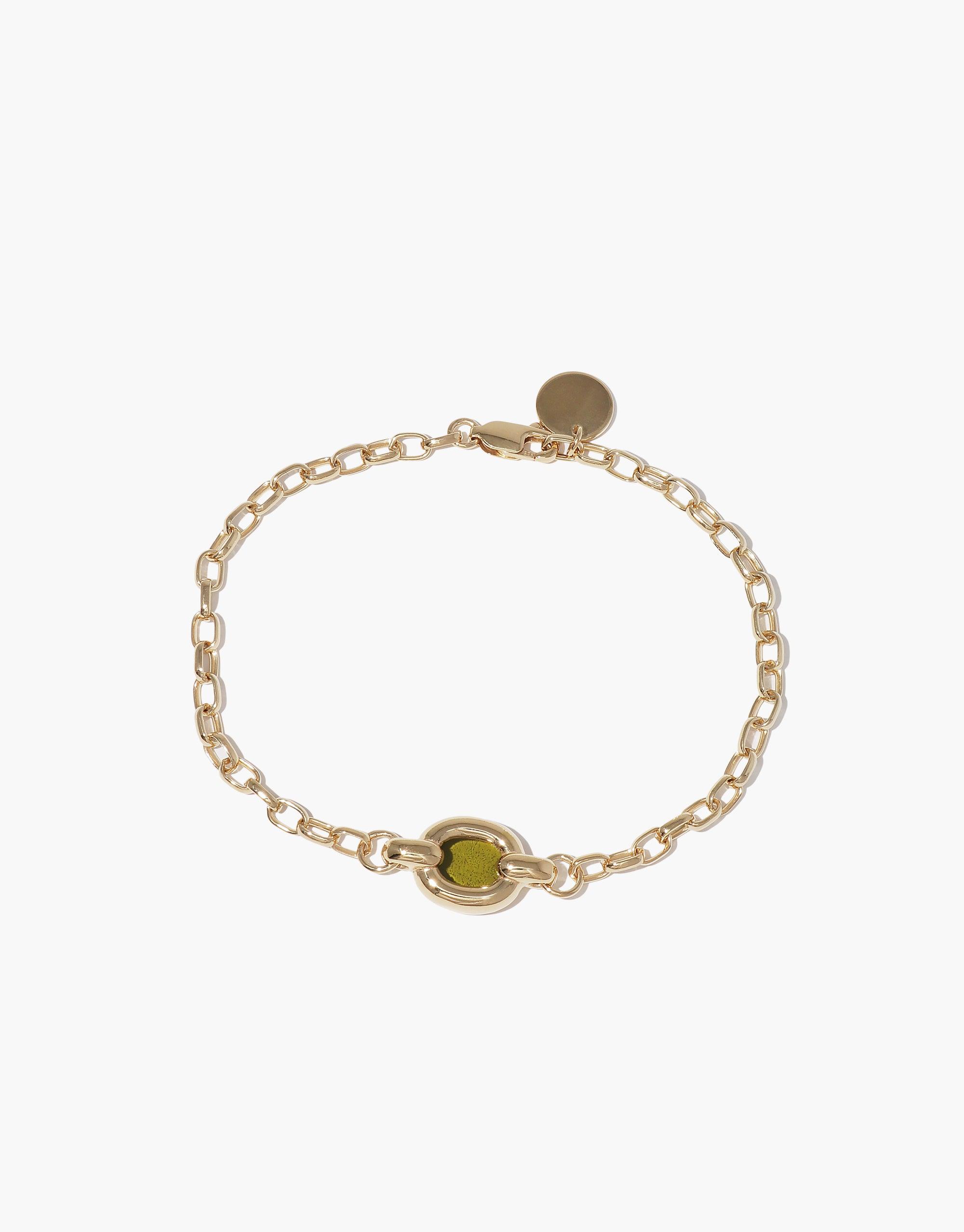 Elegant gold chain bracelet with green accent bead, showcasing sustainable design. Delicate circular charm adds sophistication. Core Loop Bracelet symbolizes unity and upcycling ethos. Versatile accessory for conscious fashion enthusiasts. CLED Core Loop Bracelet.