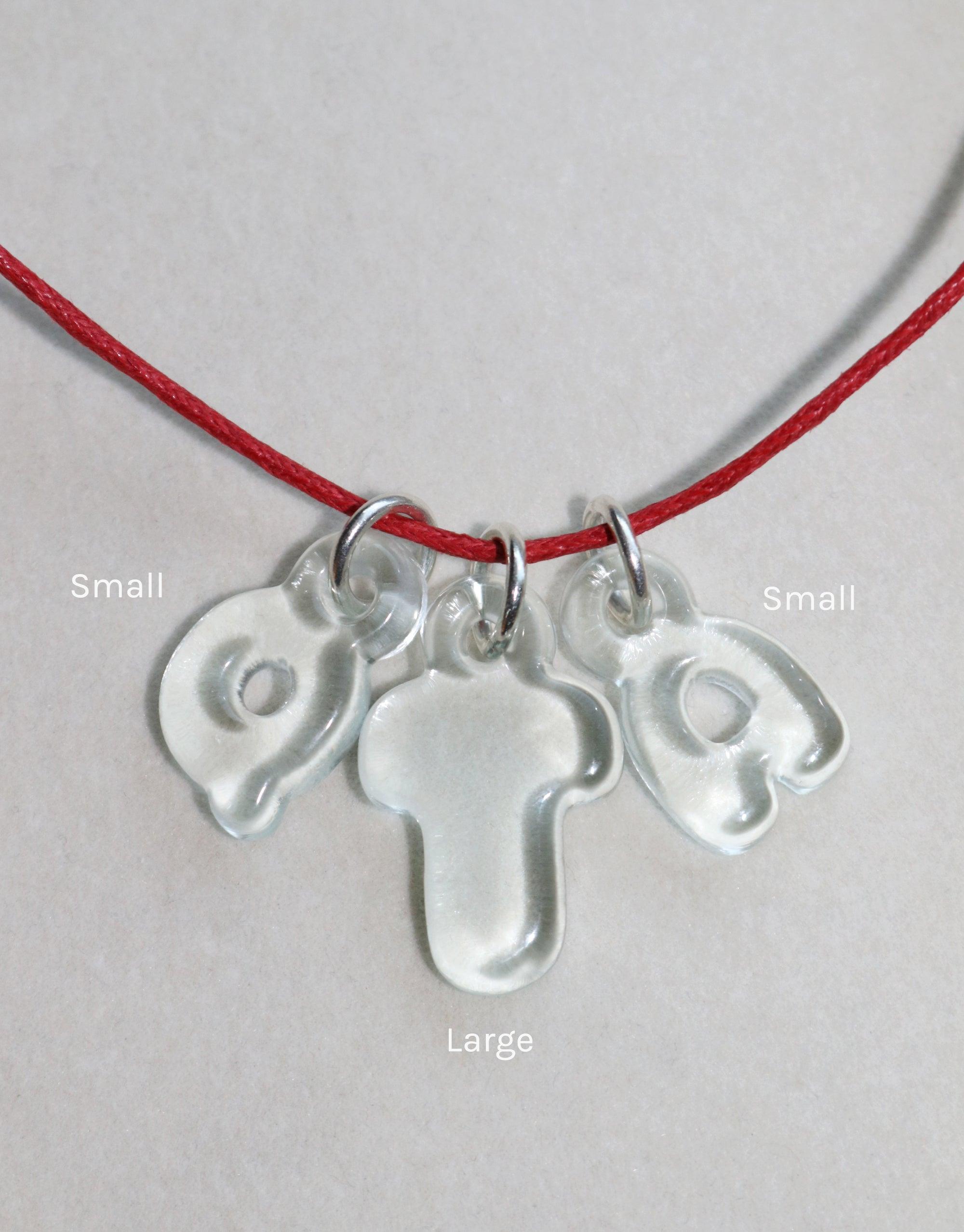 Transparent bubble letter charms on red cord necklace, showcasing eco-friendly design made from recycled glass. Playful and personalized jewelry piece for unique expression. Letter Charm | Alphabet by CLED