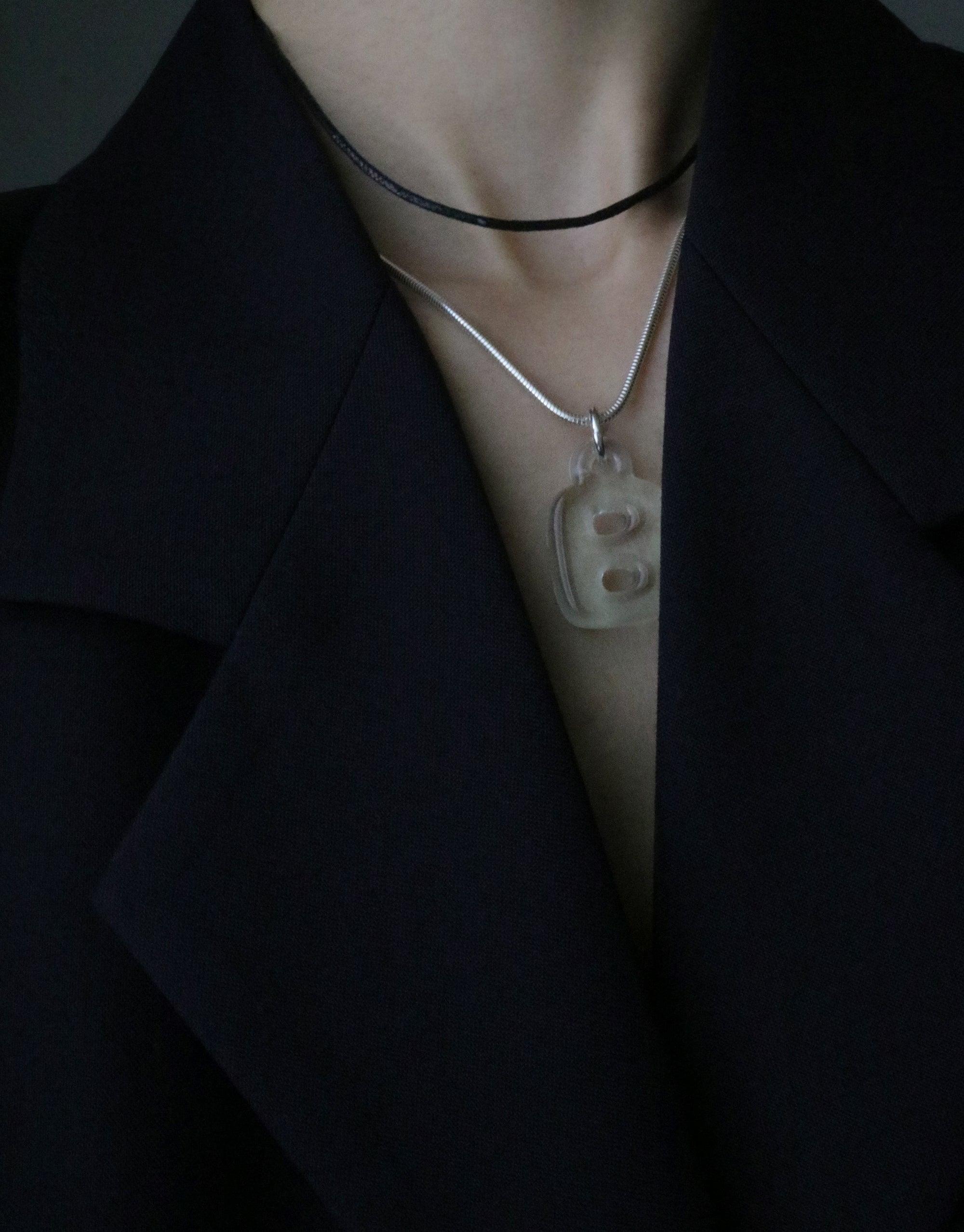 Close-up of Snake Chain Necklace worn with a pendant, showcasing its versatile styling against a black lapel. Adjustable length for perfect fit, ideal for pairing with various charms. Elegant accessory for any outfit. Snake Chain Necklace by CLED.