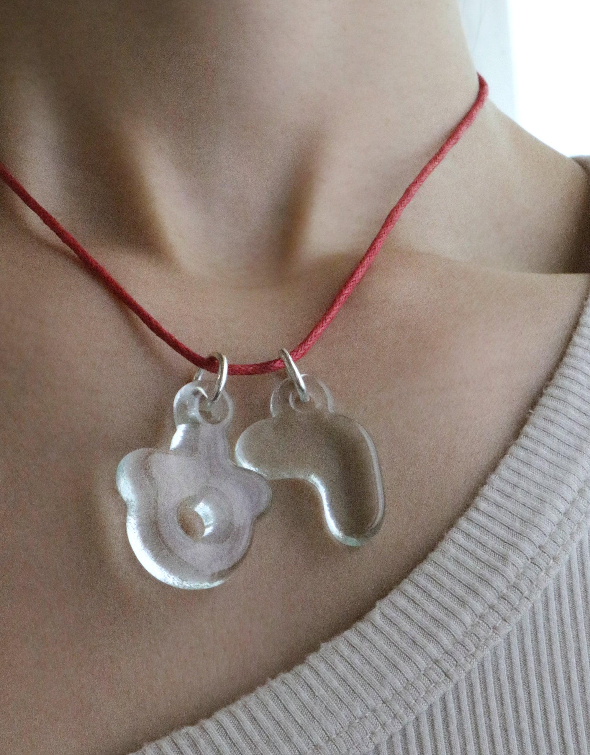 Eco-friendly bubble letter charms on red cord necklace. Transparent glass pendants in unique shapes, showcasing sustainable jewelry design. Perfect for expressing personal style and cultural identity. Letter Charm | 한글 Hangul by CLED.