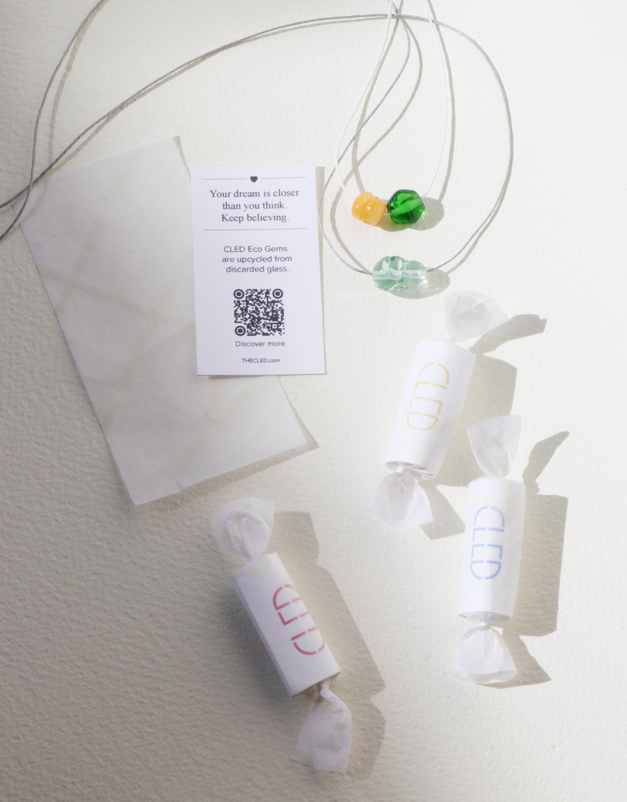 A necklace featuring a colorful glass pendant alongside a small fortune paper and candy