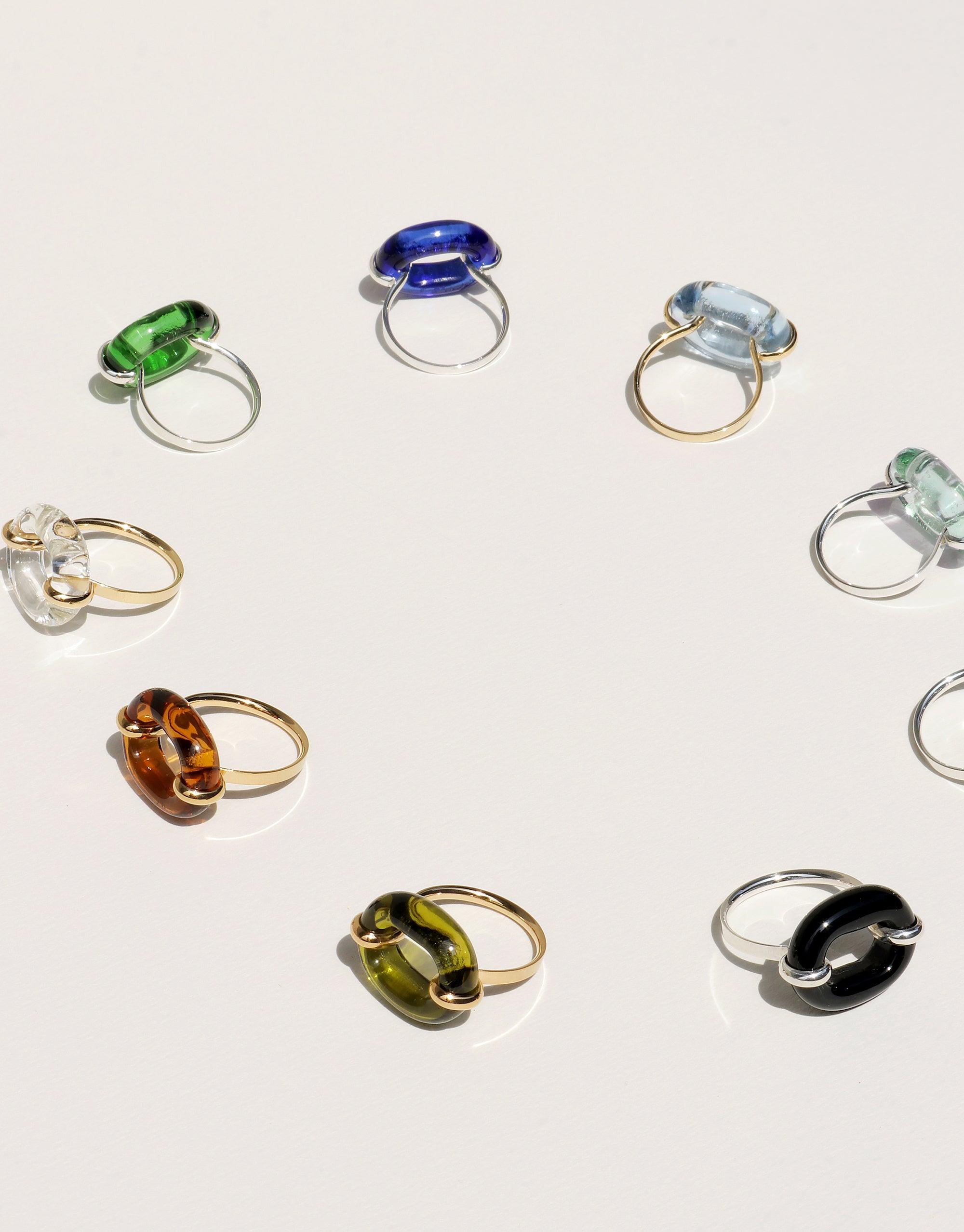 Collection of colorful glass rings showcasing various hues and styles, including the In The Loop Ring in Limited Edition "JOY on York" aquamarine color. Sustainable and upcycled jewelry pieces by CLED