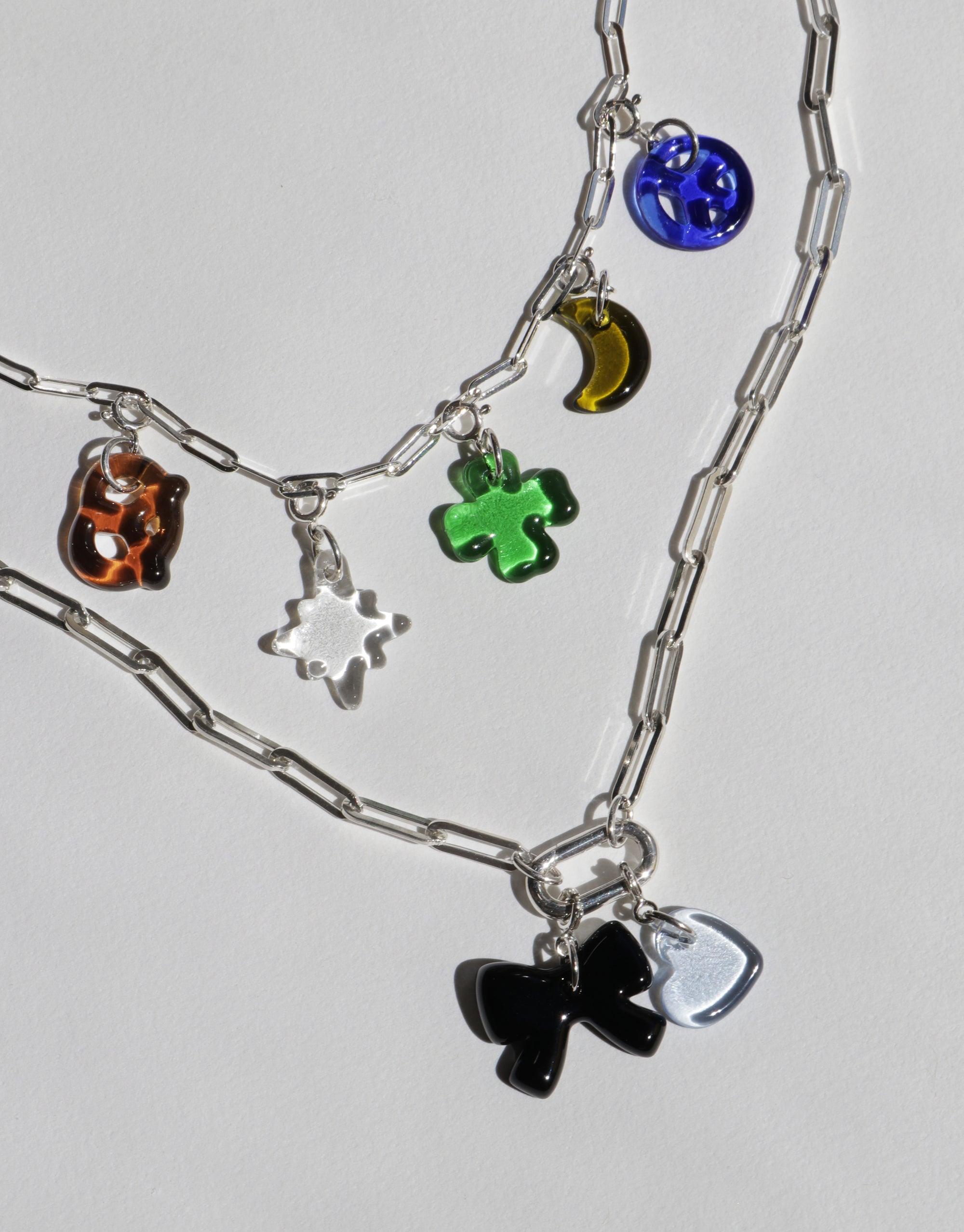 Silver chain necklace with colorful glass charms including blue sphere, green clover, orange cube, and black bow. Layered design for customizable styling. Icon Chain Necklace | E by CLED