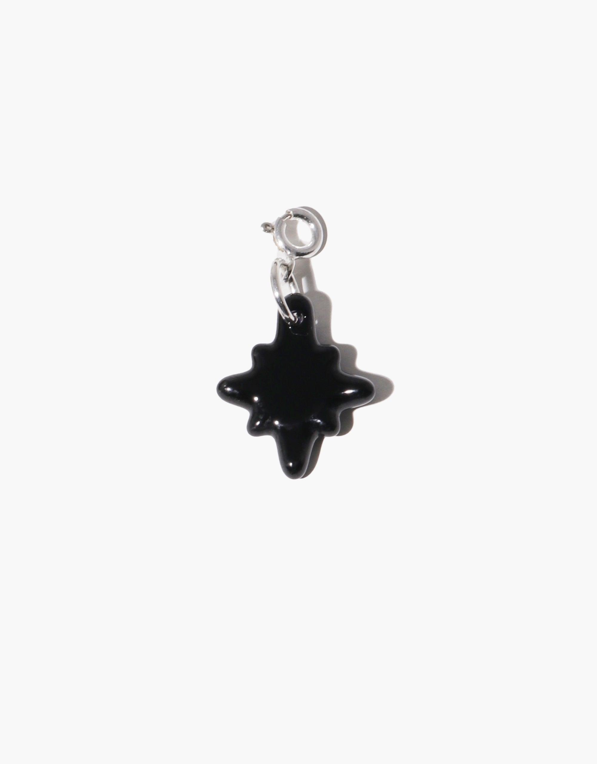 Stylish black star-shaped charm with silver clasp, perfect for adding a celestial touch to jewelry. Sparkle B Icon Charm showcases distinctive shape, ideal for enhancing necklaces or bracelets. CLED
