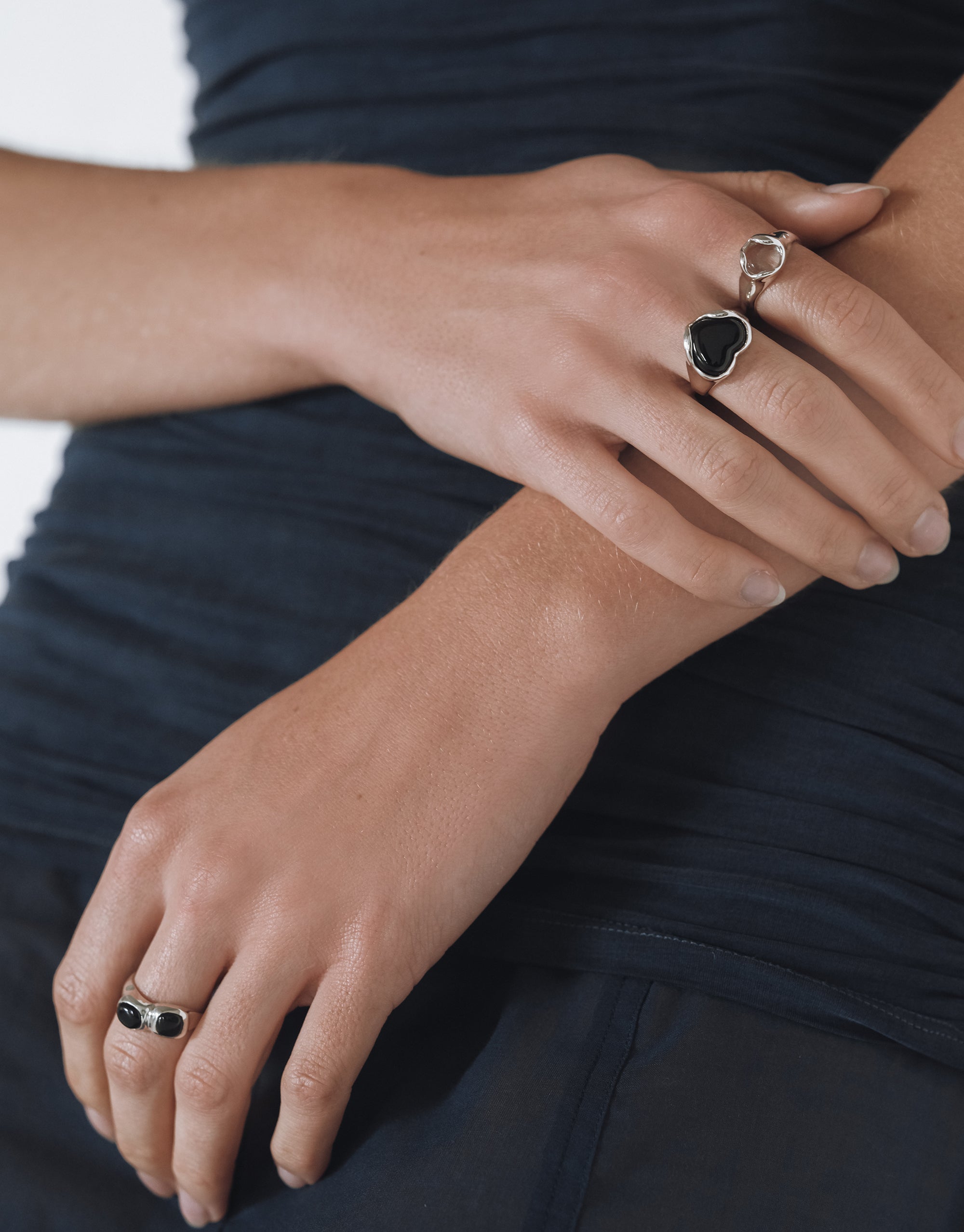 Close up of a model’s wrist showcasing a silver bracelet featuring a soft blue eco gem paired with a matching pendant necklace. The jewelry is set against a light background that highlights its delicate details and modern design.