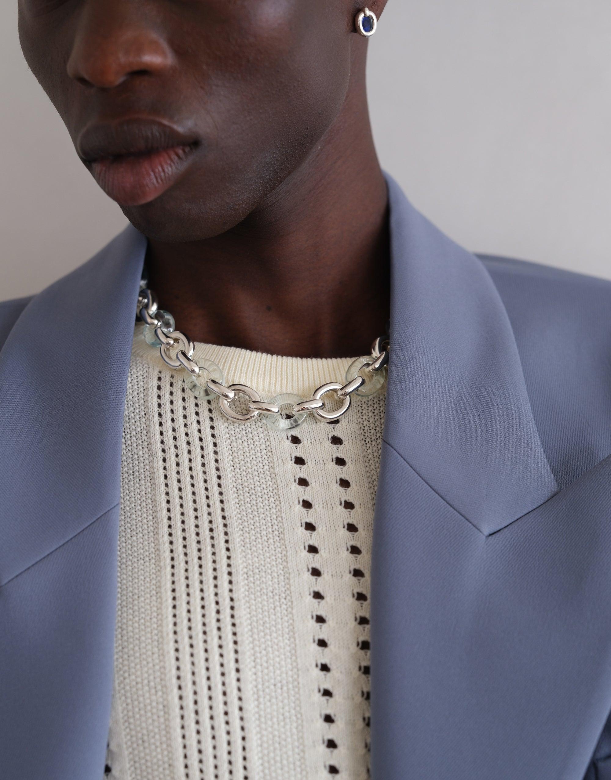 Close-up of model wearing Connected Loop Necklace, showcasing mixed metal chain against cream sweater and blue blazer. Stylish upcycled jewelry symbolizing unity and connection. Connected Loop Necklace | Mixed Metal & Glass by CLED
