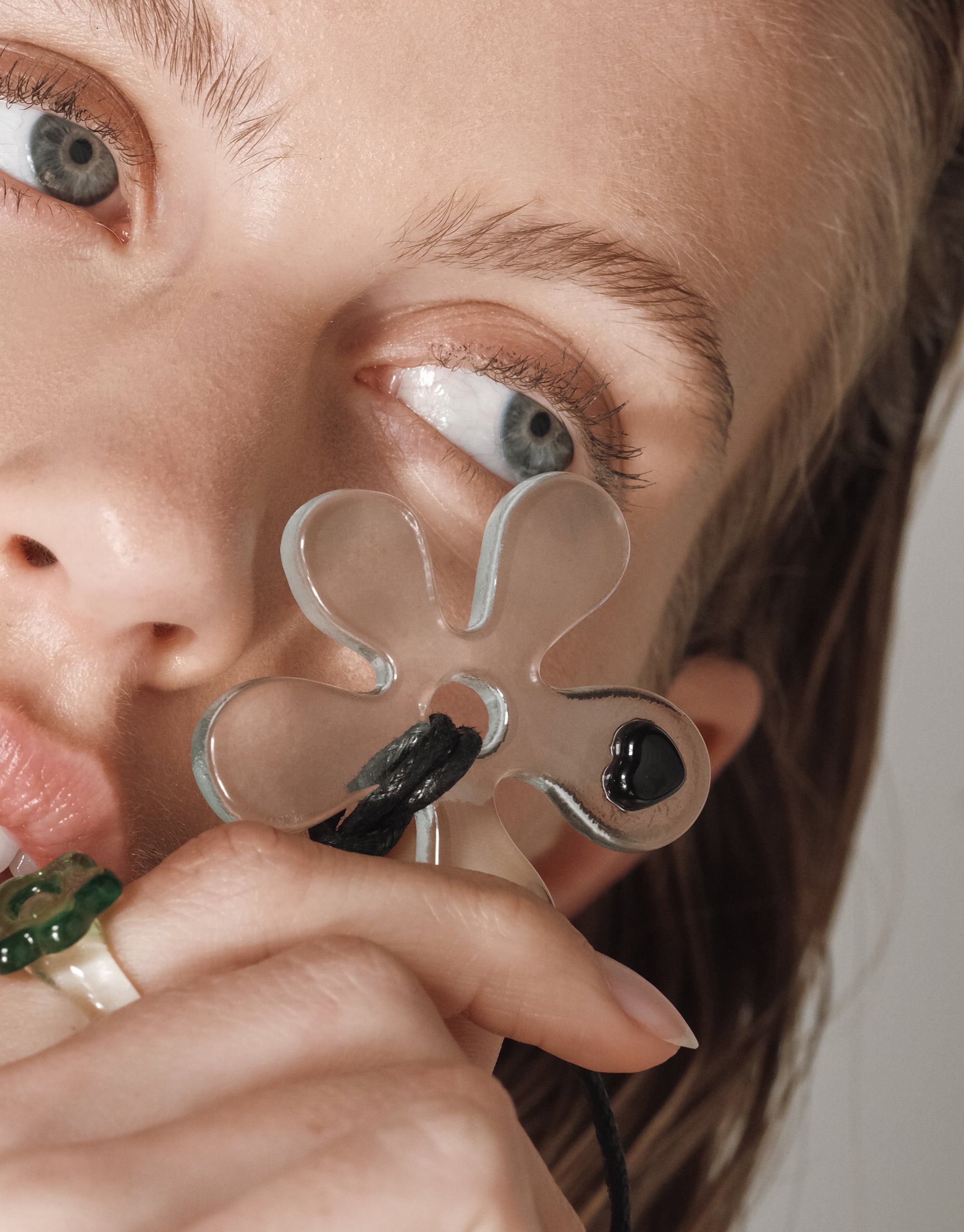 Clear glass Petal Sculpture Necklace with heart detail shown against model's face, featuring flowing rounded petals - by CLED