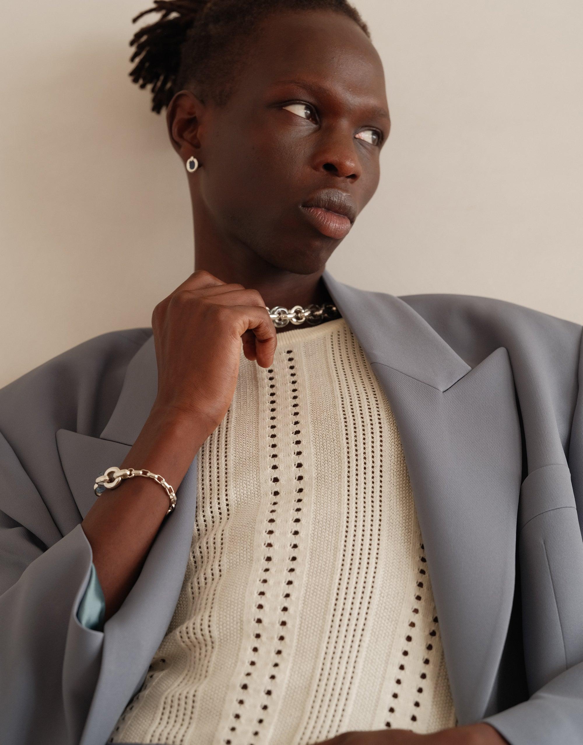 Model wearing small Core Loop Earrings with gray blazer and cream knit sweater, showcasing elegant simplicity and versatility of the jewelry. Upcycled design embodies CLED's commitment to sustainability and unity. Core Loop Earrings | Small by CLED