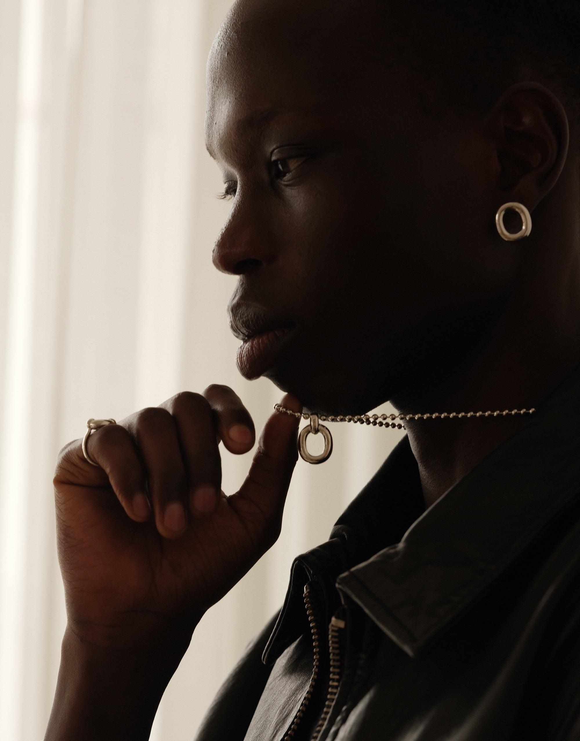 Profile view of a person wearing a sleek ball chain necklace with circular pendant, showcasing the elegant Core Loop Necklace design. The necklace complements the wearer's stylish appearance, embodying unity and upcycled fashion. CLED Core Loop Necklace | Ball Chain