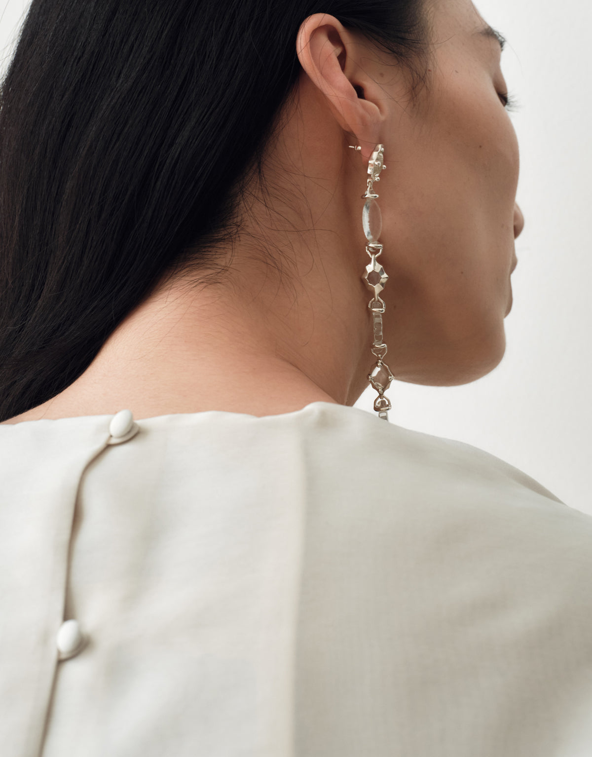 Cadence Linear Earring in clear glass worn in profile, a long line of graduating upcycled glass Eco Gems in sterling silver. Cadence Linear Earring by CLED.
