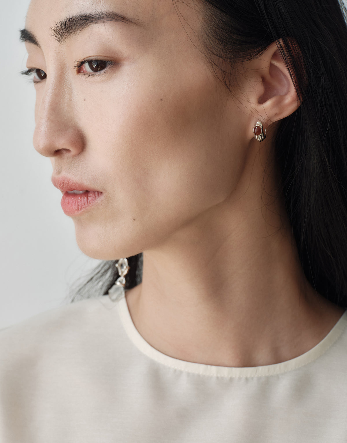 Cadence Linear Earring in clear glass worn as a single long drop, graduating Eco Gems linked along a sterling silver line. Upcycled glass handmade in Los Angeles. Cadence Linear Earring by CLED.