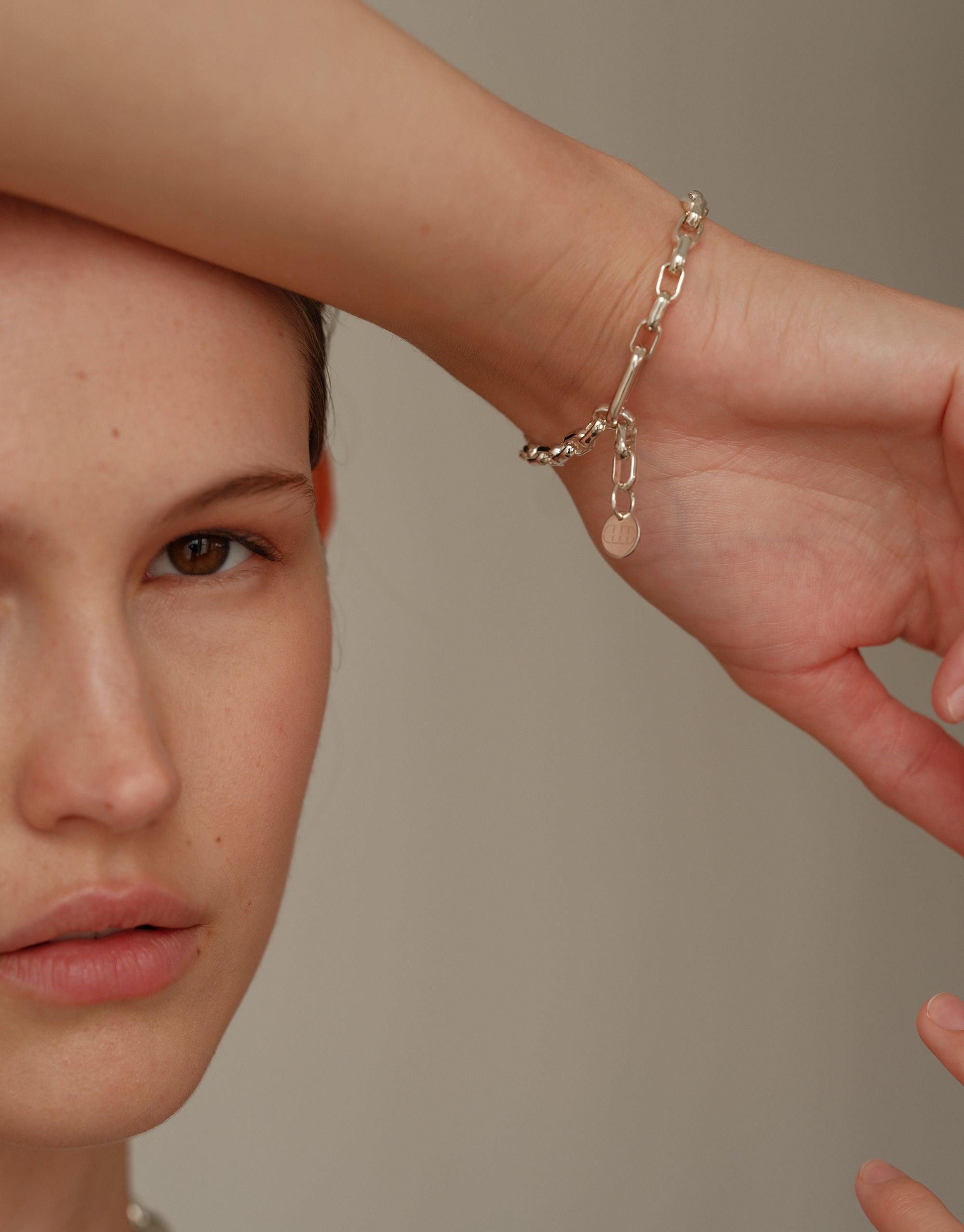 Elegant silver Loop Chain Bracelet with delicate heart charm, showcasing upcycled design on model's wrist. Symbolizes unity and connection in CLED's In The Loop collection. Loop Chain Bracelet by CLED.