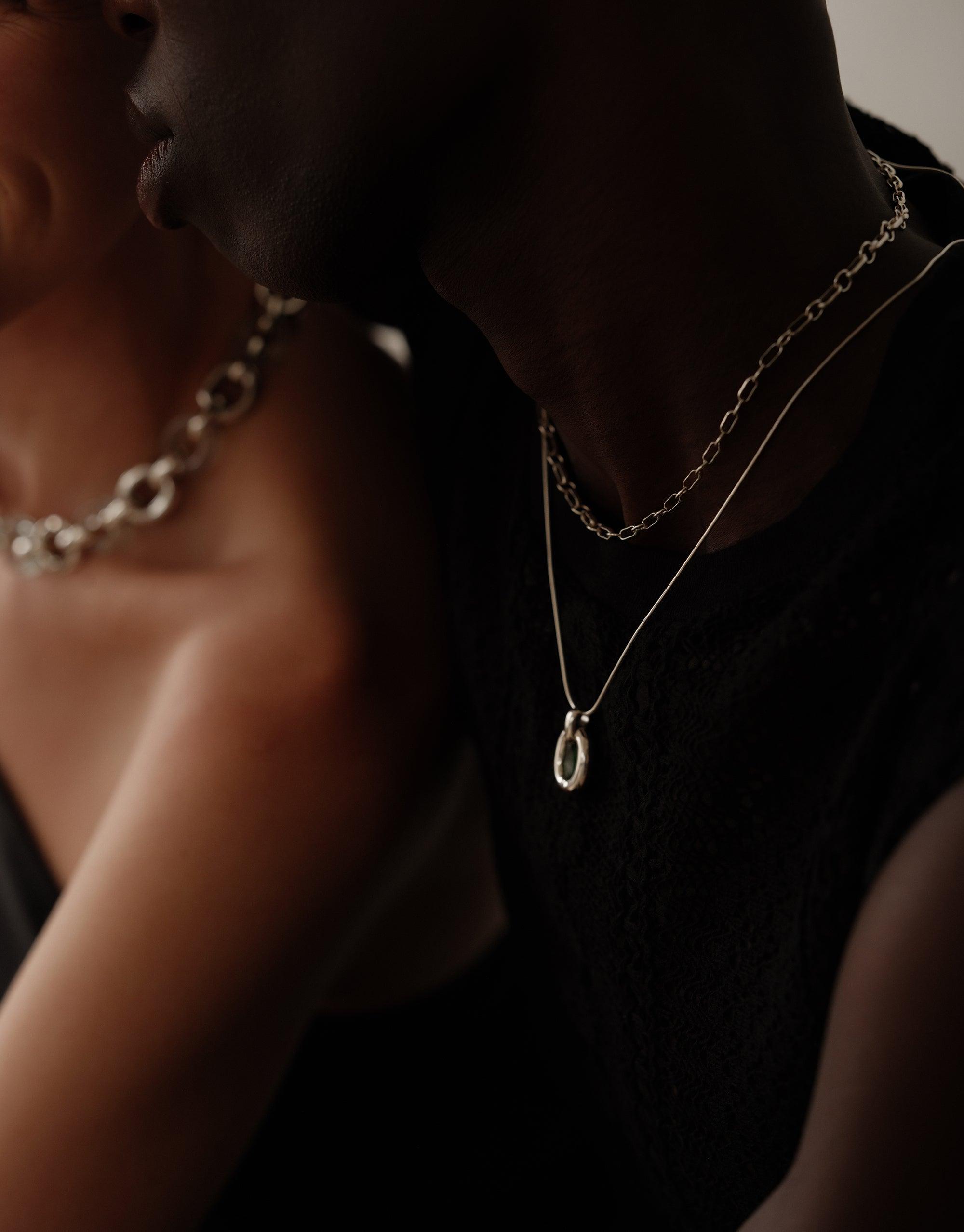 Elegant Core Loop Necklace with Snake Chain layered over dark clothing, showcasing delicate pendant and intricate chain design. Upcycled jewelry symbolizing unity and connection. Sustainable fashion piece from the Loop Collection. Core Loop Necklace | Snake Chain by CLED