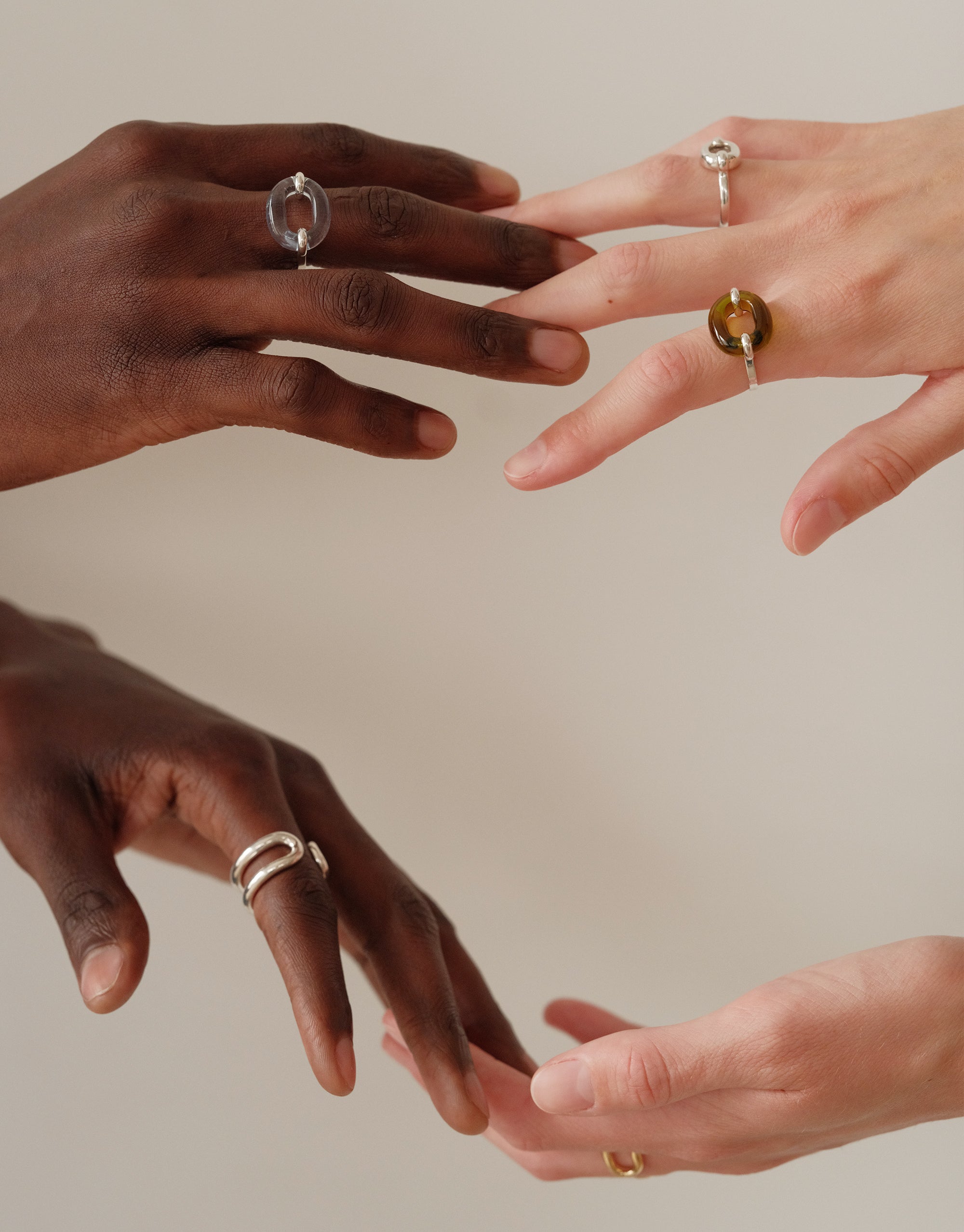 Two hands of different skin tones gently touching, showcasing the Loop Chain Bracelet on one wrist. A symbol of unity and connection, representing CLED's upcycling mission and the In The Loop collection. Loop Chain Bracelet by CLED.