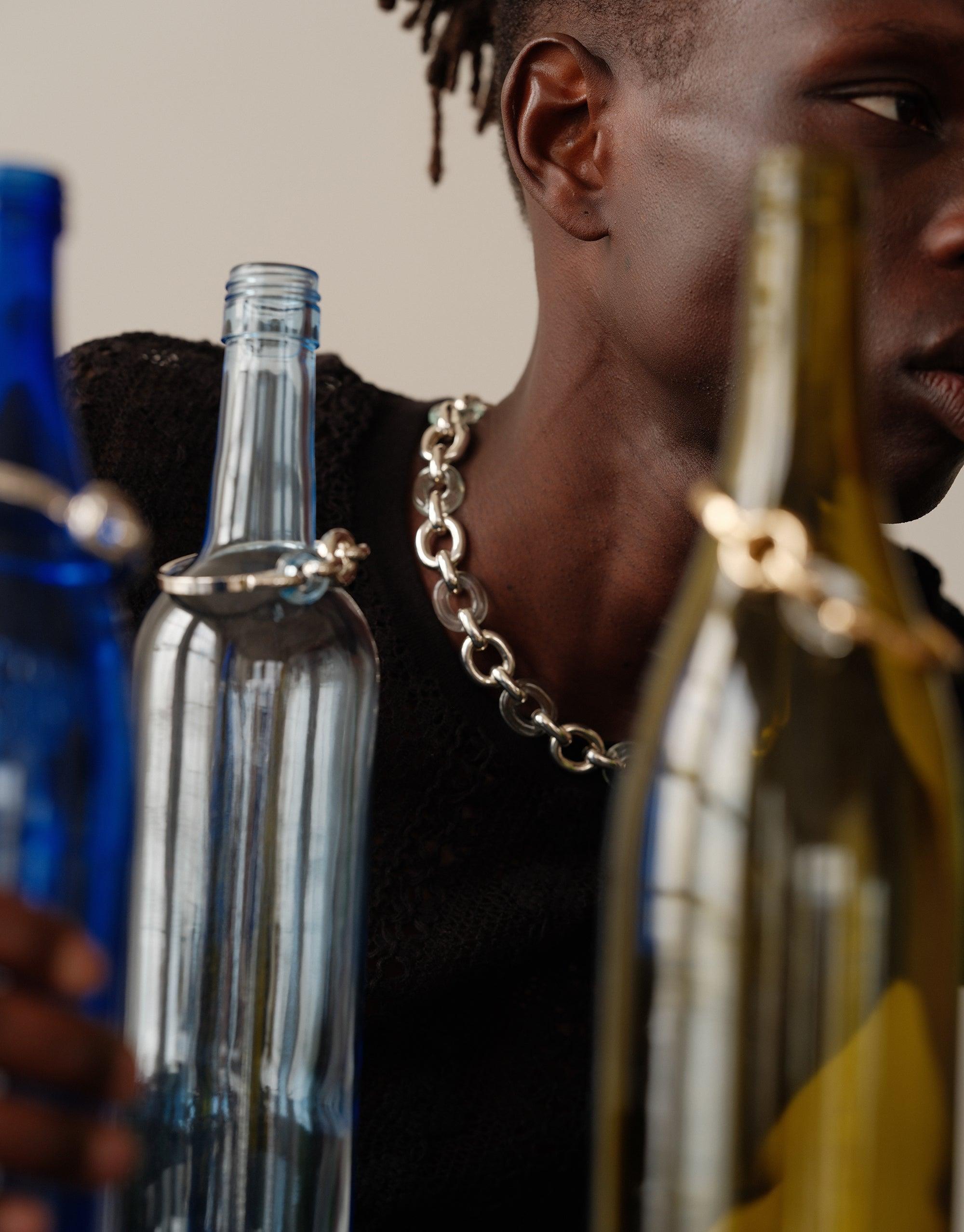 Connected Loop Necklace showcased with upcycled glass bottles, highlighting the mixed metal chain design. Sustainable jewelry from the In The Loop collection symbolizing unity and environmental consciousness. Connected Loop Necklace | Mixed Metal & Glass by CLED.