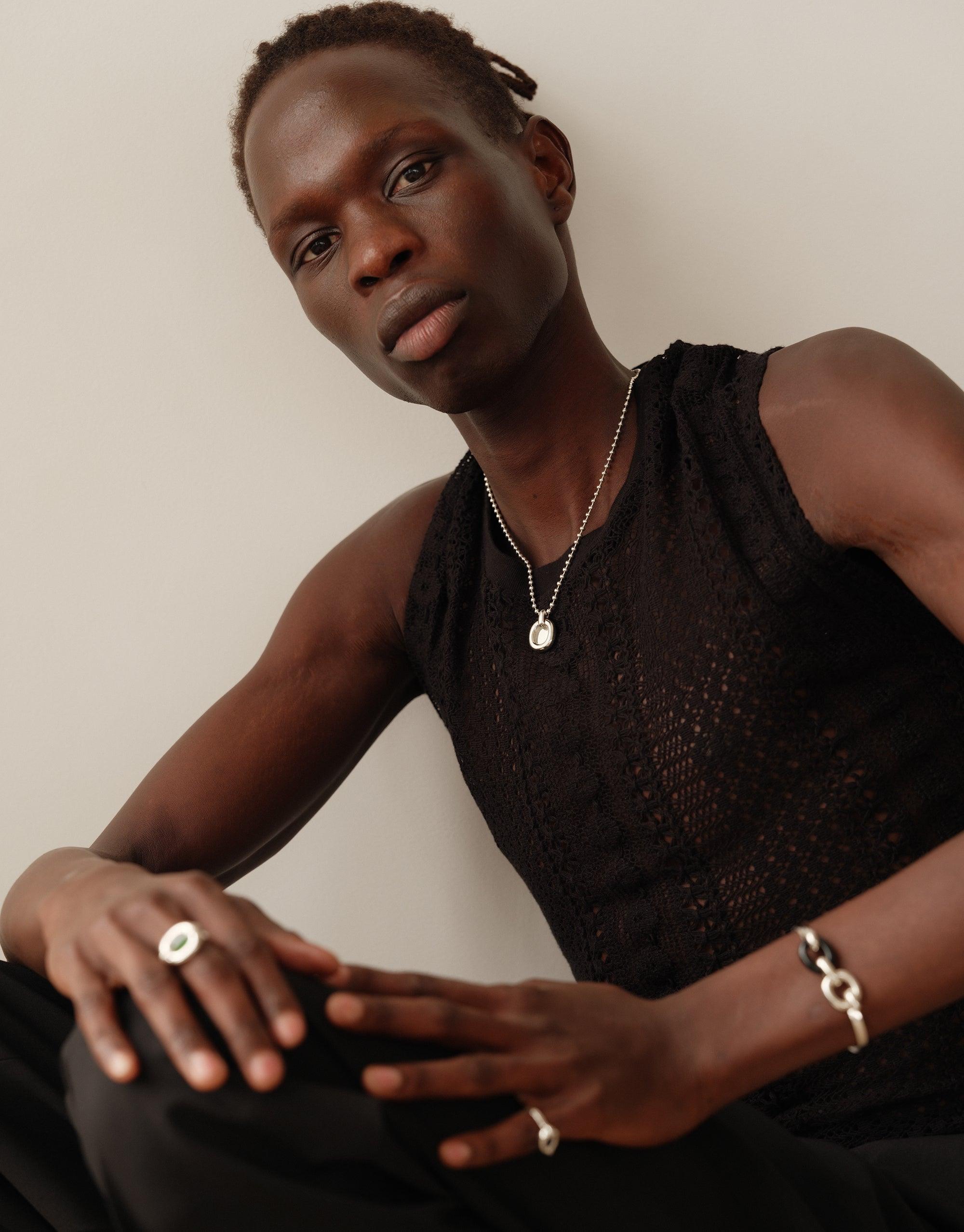 Model wearing Core Loop Necklace | Ball Chain, showcasing delicate silver pendant on sleek chain. Paired with textured black sleeveless top and matching accessories, demonstrating versatile style. Embodying unity and upcycling ethos of CLED's Loop Collection.