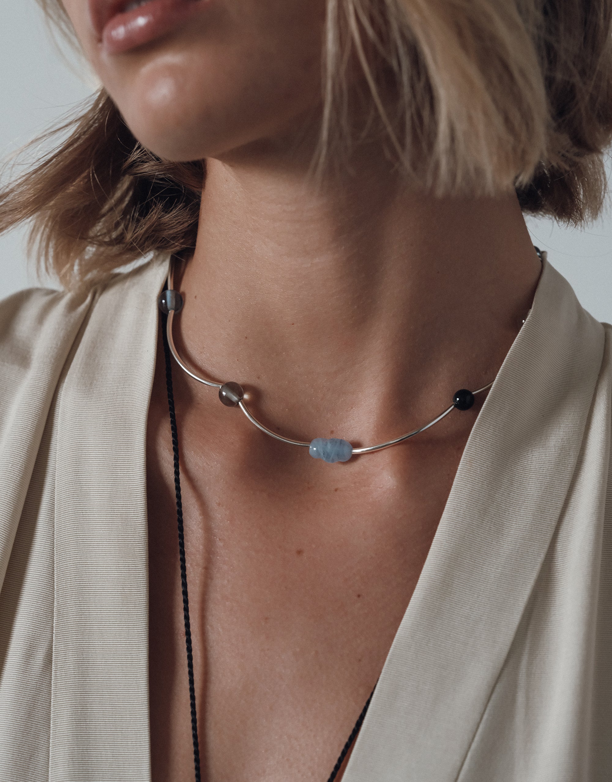 Halo Necklace featuring curved silver and blue glass beads on elegant neckline, styled with cream silk robe - CLED