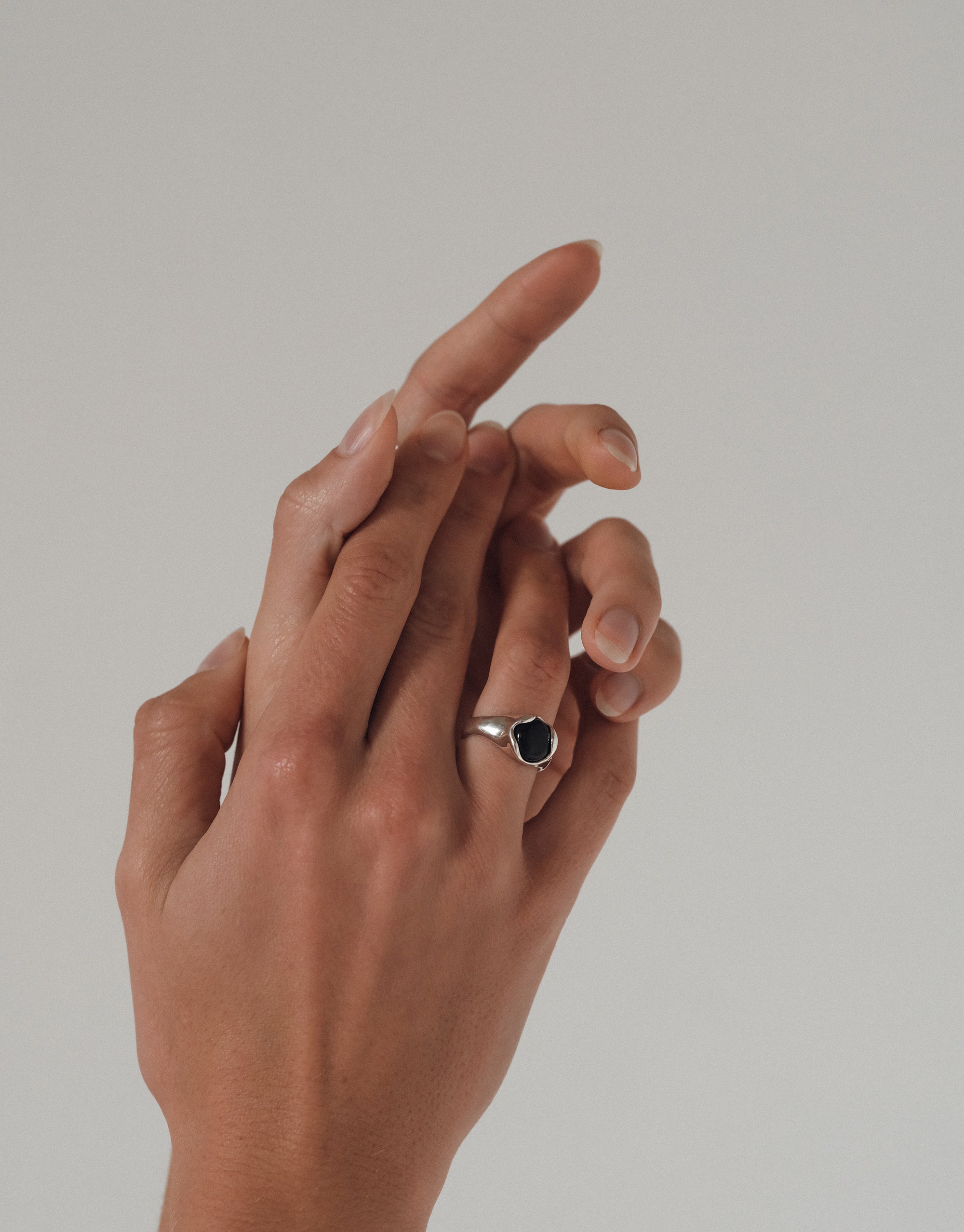Elegant Orb Ring with dark center stone set in silver band, shown on graceful hand against neutral background - CLED