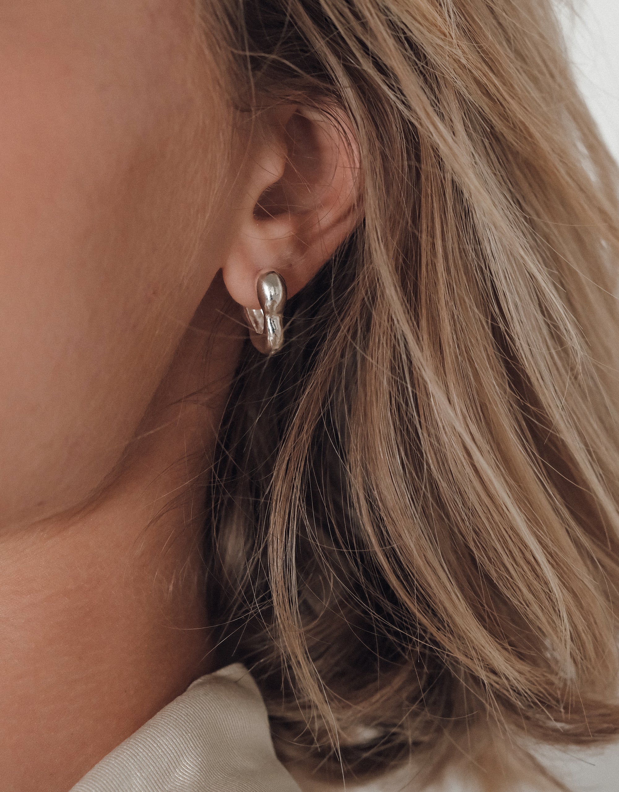 Flow Hoop Earrings with sculptural curved design shown on model, featuring elegant undulating silver form by CLED