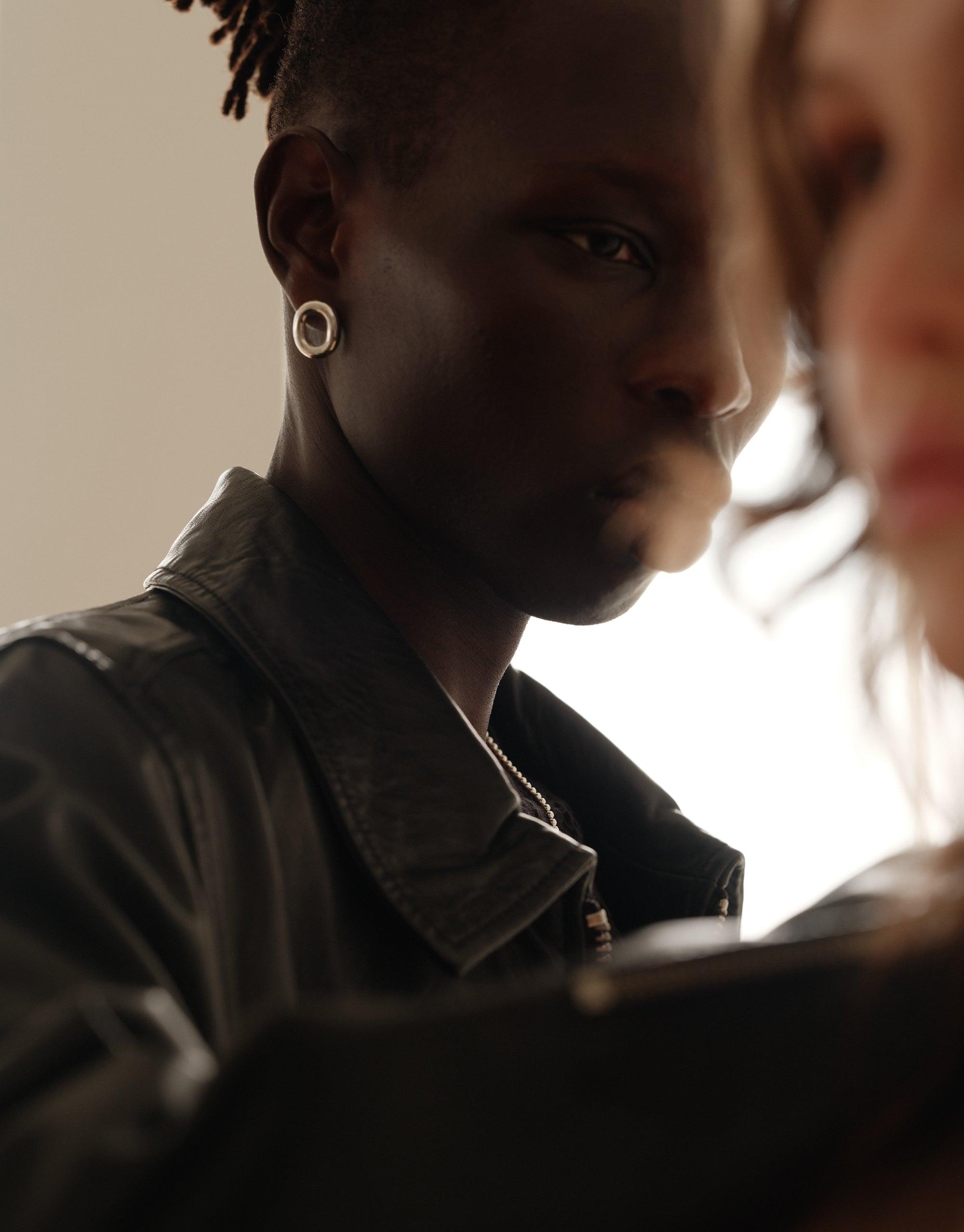 Profile view of a person wearing stylish Core Loop Earrings | Large, showcasing the elegant circular design. The earrings complement the wearer's sophisticated look, embodying unity and upcycled fashion. CLED