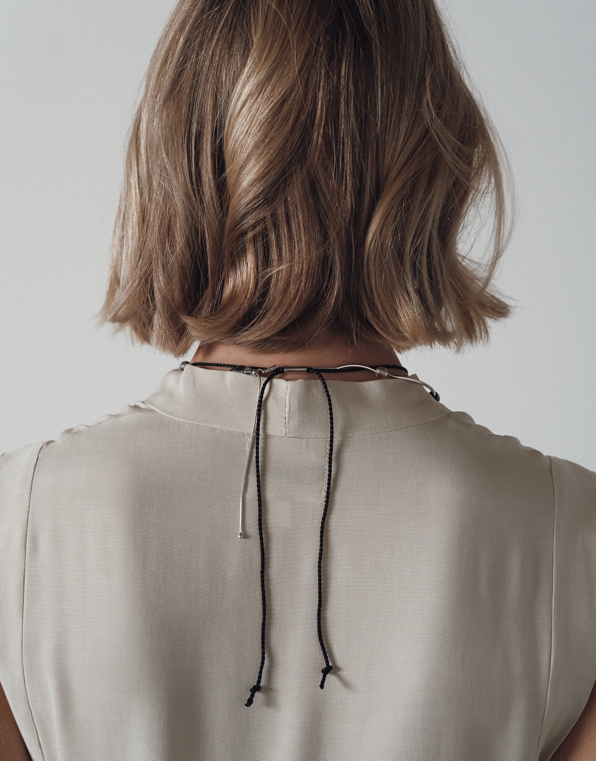 Back view of Solace Drop Necklace on cord, showing delicate black string against ivory silk top, by CLED