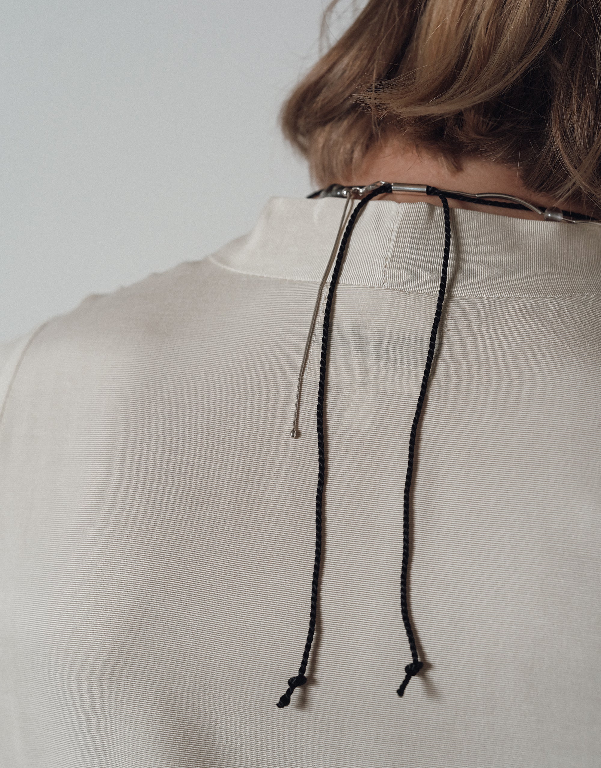 Solace Drop Necklace with black cord elegantly draped across a white linen top, showcasing minimalist design by CLED