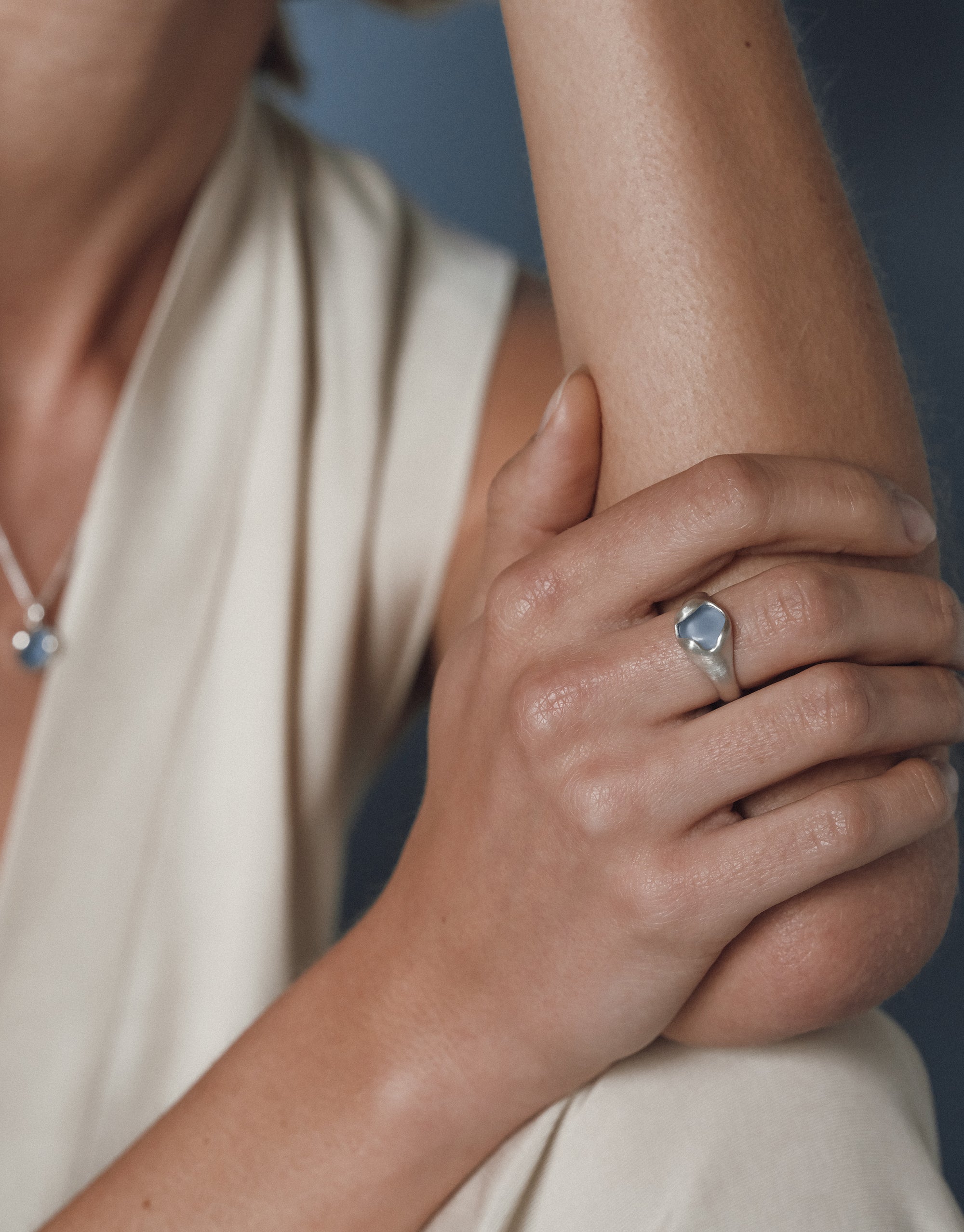 Elegant Orb Ring with silver setting and blue eco gem center stone worn on hand against cream fabric by CLED