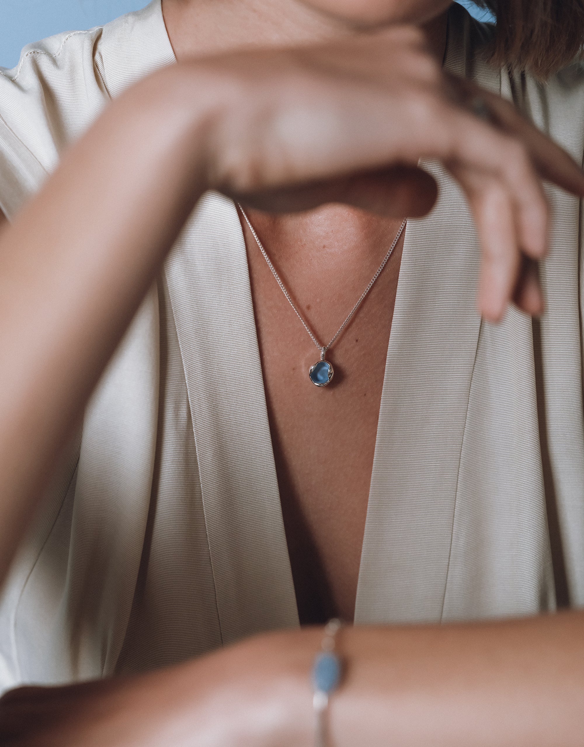 Minimalist Goyo Orb Necklace with blue glass pendant on delicate silver chain against cream silk blazer by CLED