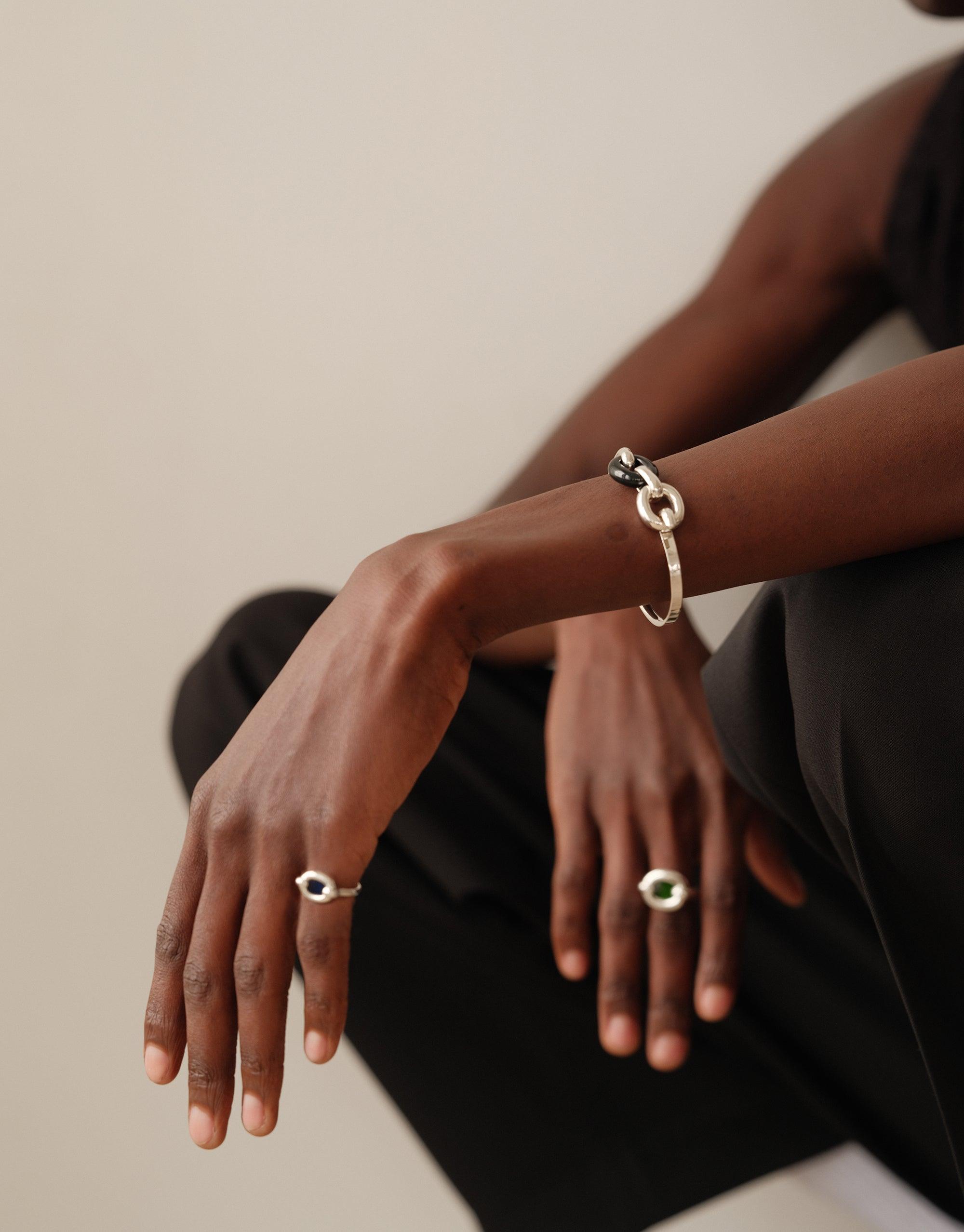 Elegant Loop Hook Bracelet adorning a wrist, showcasing its minimalist design and symbolizing unity. Paired with matching rings, this sustainable jewelry piece from the In The Loop collection embodies connection and upcycling. Loop Hook Bracelet by CLED.