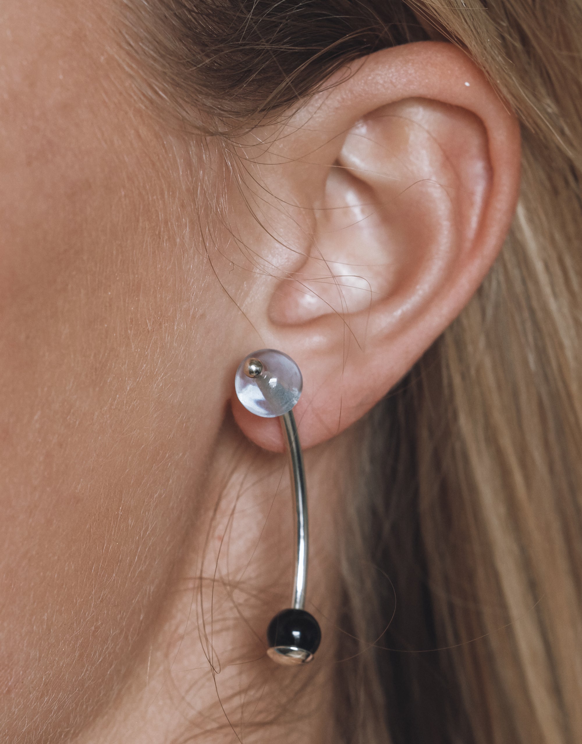 Halo Earrings: Modern curved silver design with clear and black glass spheres, showing elegant asymmetrical styling - CLED