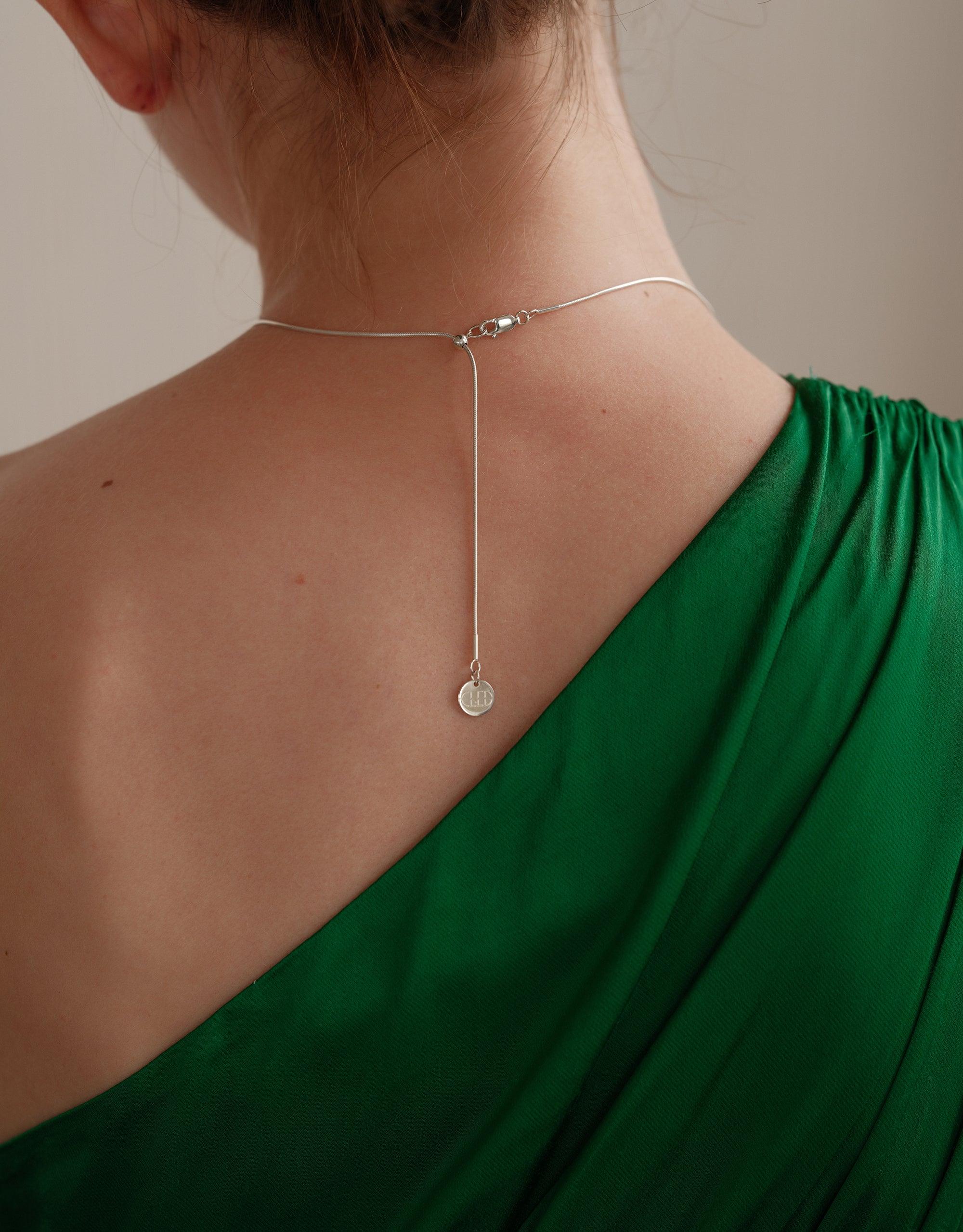 Elegant Core Loop Necklace with delicate snake chain and pendant, worn on a model in a green one-shoulder top. The necklace showcases a minimalist design, perfect for everyday wear. Part of the sustainable In The Loop collection by CLED. Core Loop Necklace | Snake Chain.