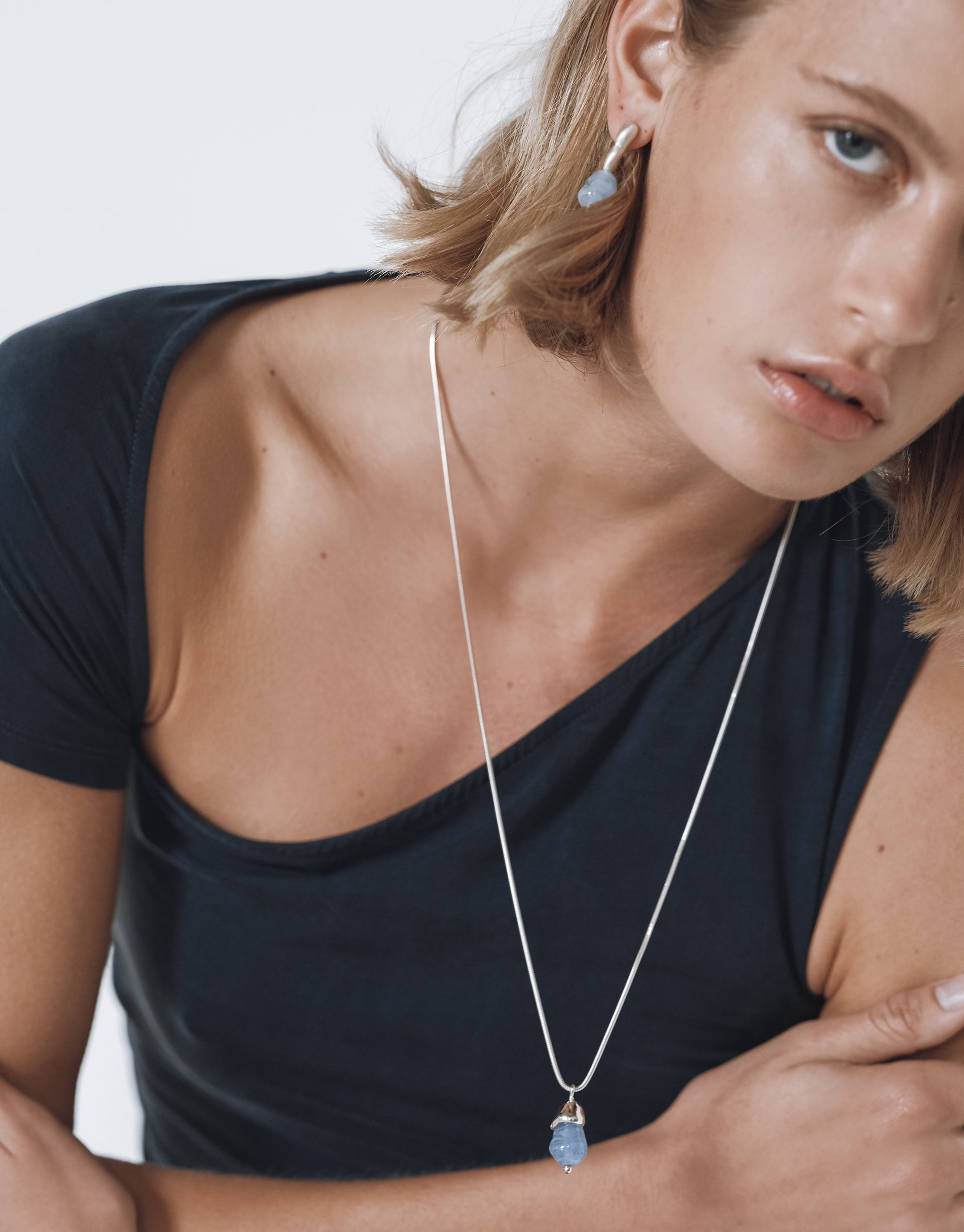 Silver snake chain necklace with blue glass drop pendant, styled with black top, showcasing Solace Drop Necklace by CLED