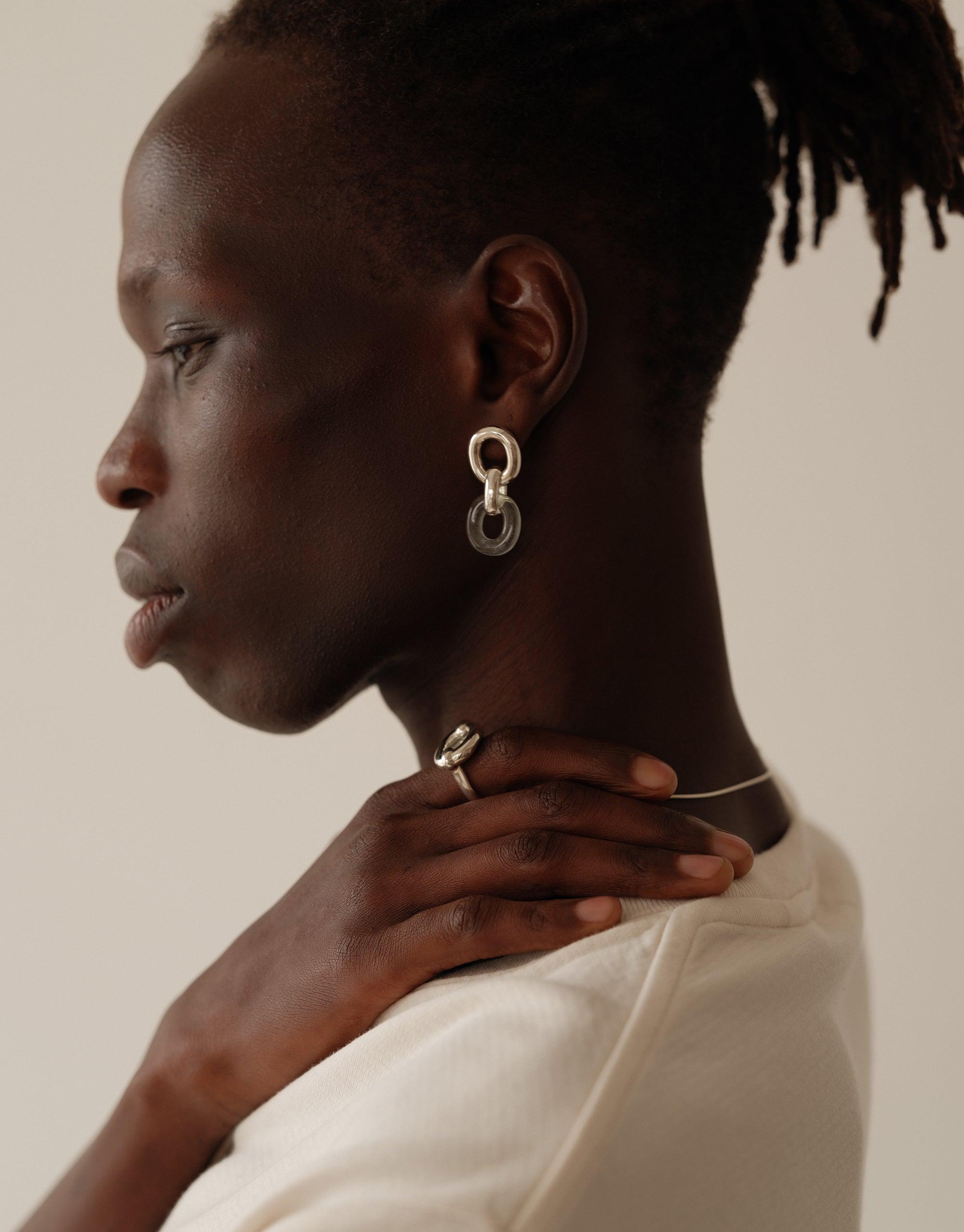 Profile view of a model wearing Connected Loop Earrings, showcasing the unique design with interlocking circles. The earrings symbolize unity and upcycling, reflecting CLED's commitment to sustainable fashion. Connected Loop Earrings by CLED.
