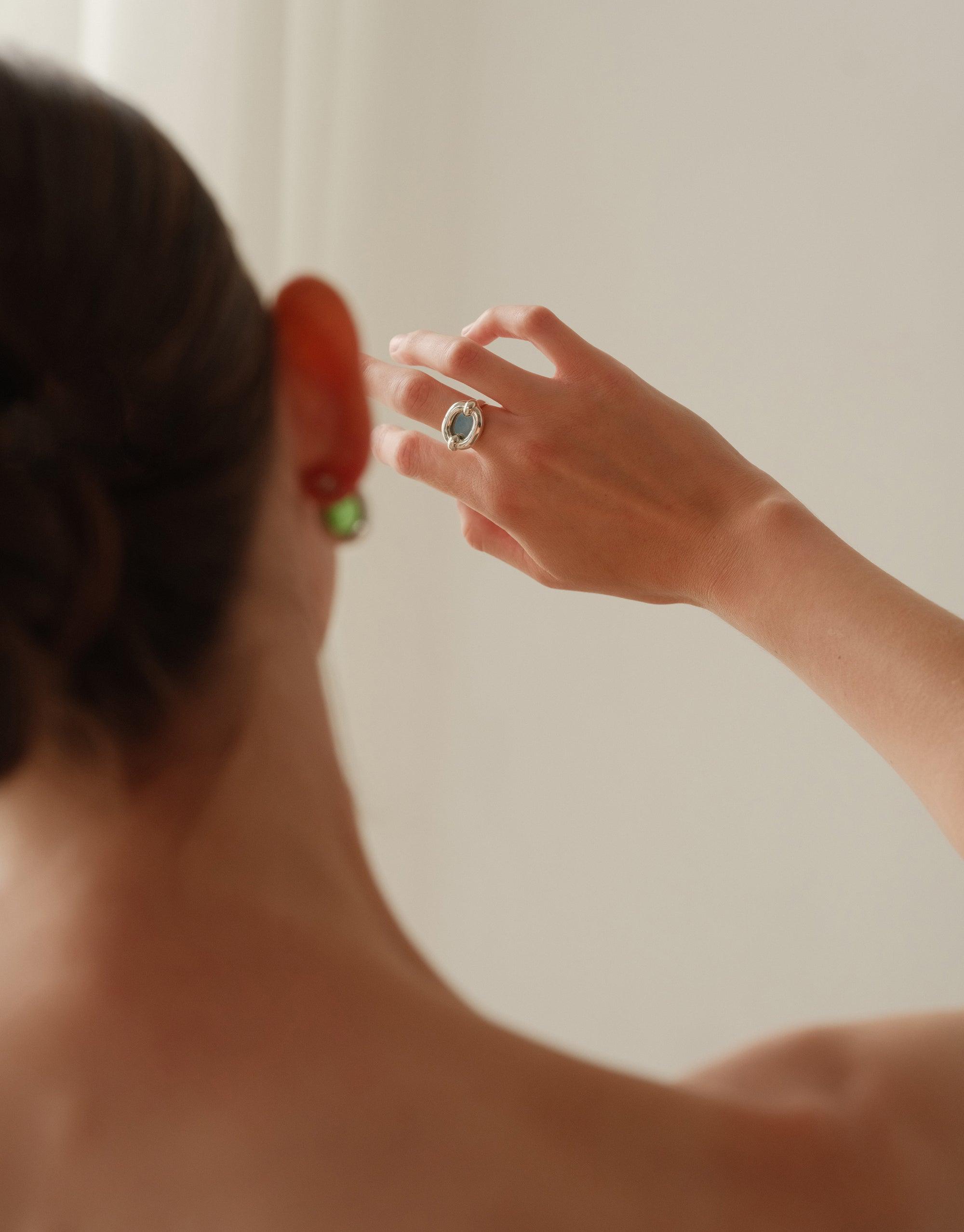 Hand wearing Core Loop Ring | Large with reflective surface, showcasing its versatile design and functionality. Elegant eco gem encased in metal setting, perfect for quick mirror checks or capturing moments. Innovative jewelry piece by CLED.
