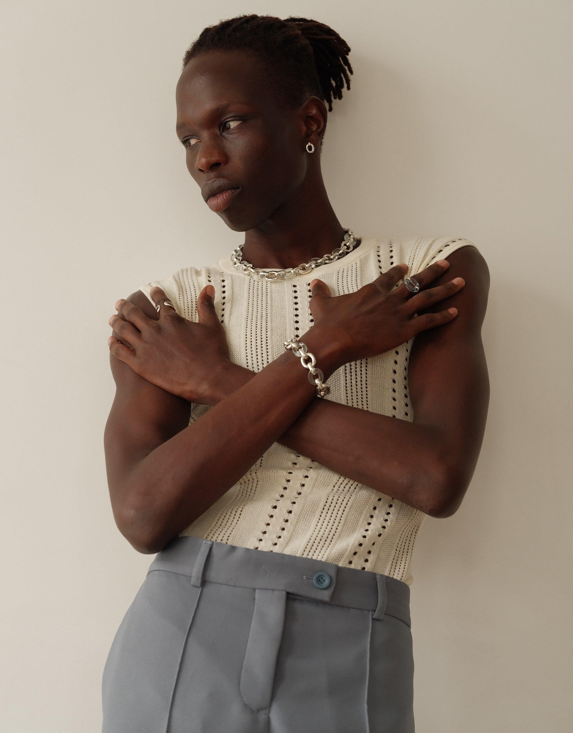 Model wearing Connected Loop Bracelet in mixed metal and glass, showcasing upcycled design on wrist. Paired with cream knit top and gray trousers, emphasizing sustainable fashion. Connected Loop Bracelet | Mixed Metal & Glass by CLED
