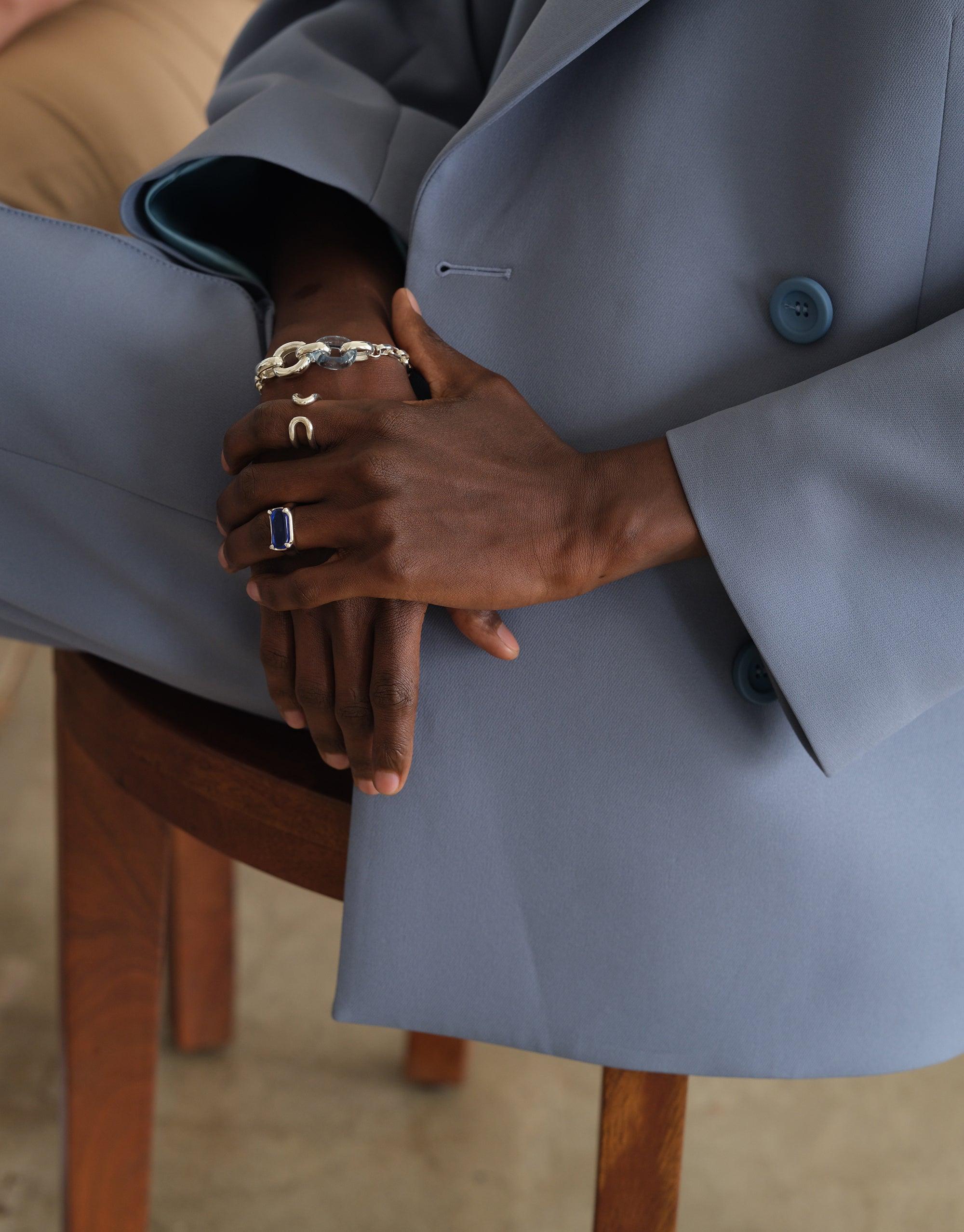 Elegant Loop Chain Bracelet adorning a wrist, showcasing its intricate design against a stylish grey suit backdrop. A symbol of unity and upcycling craftsmanship in sustainable jewelry. Loop Chain Bracelet by CLED