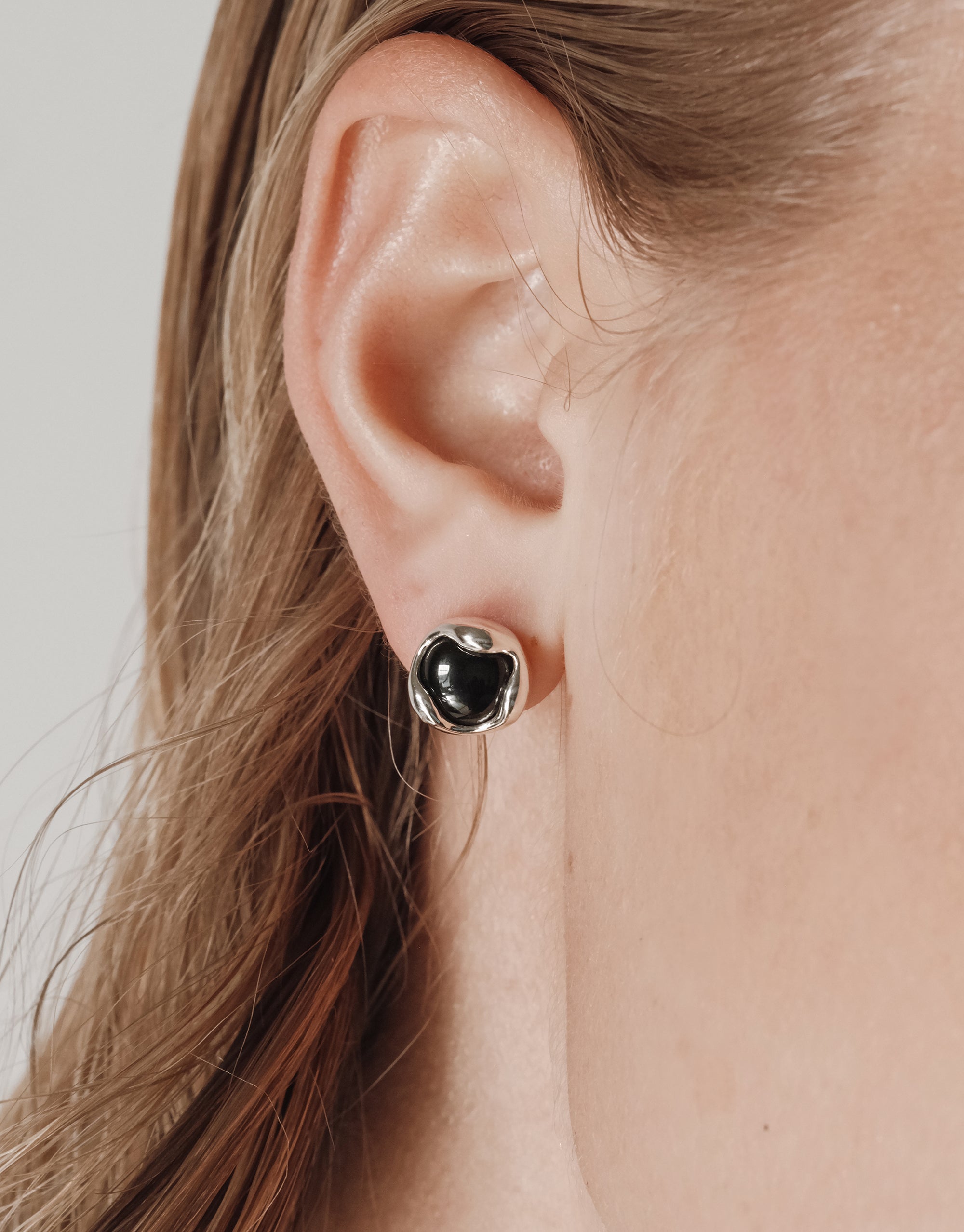 Minimalist silver Orb Stud Earrings with black eco-friendly stone in curved bezel setting worn on ear - CLED